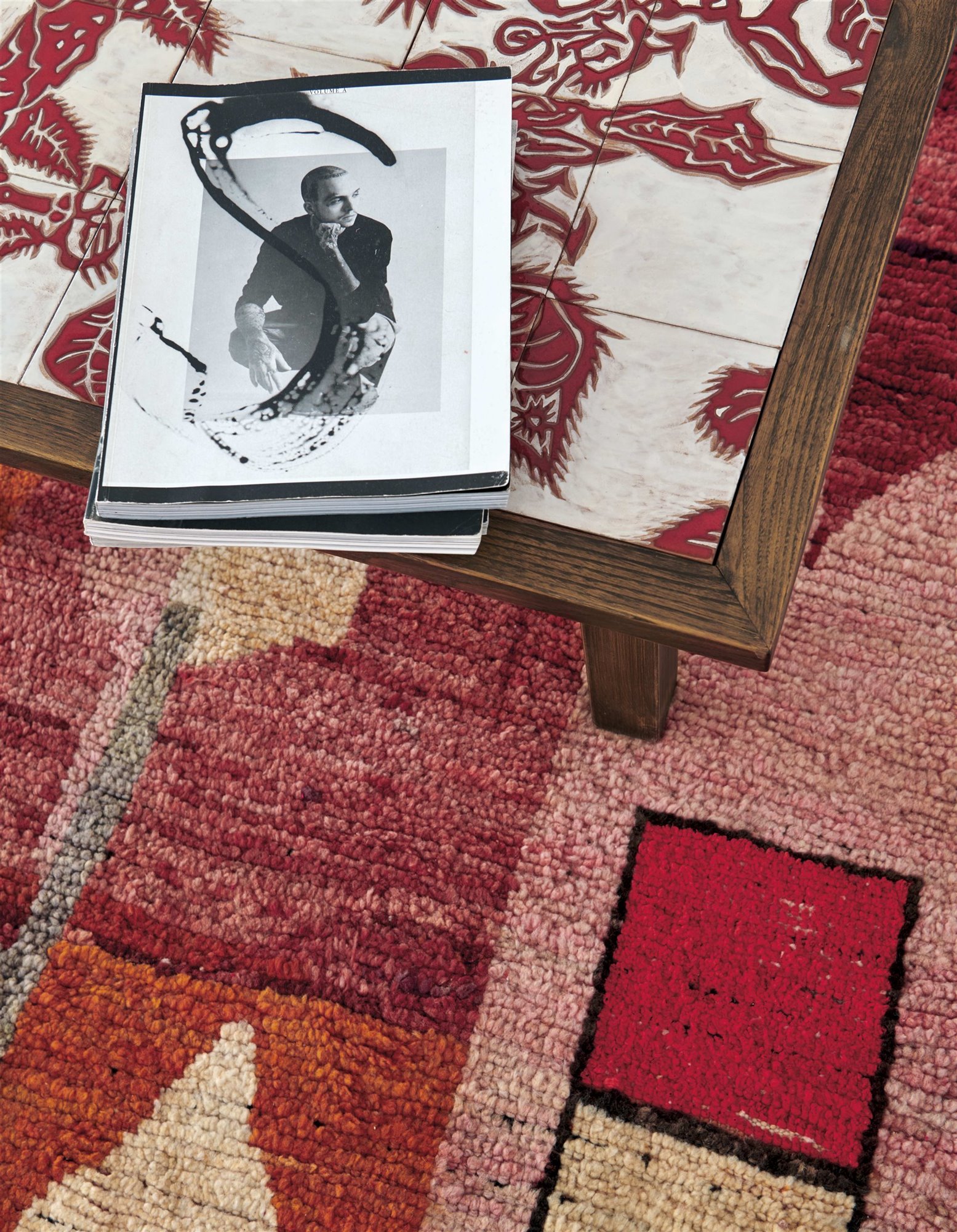 mesa de café de azulejos y madera con revista encima de una alfombra marroquí