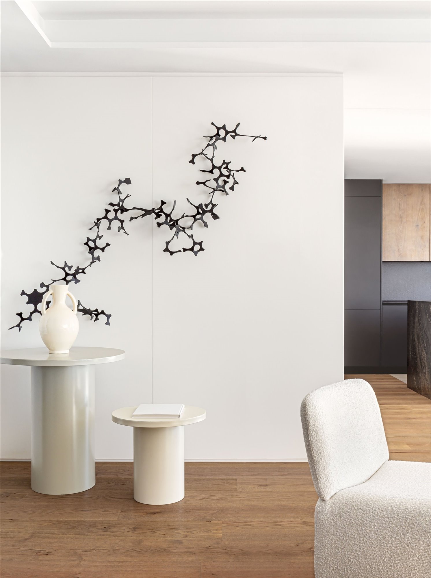 salón blanco elegante y minimalista con butaca, mesa auxiliar con forma de columna y botijo