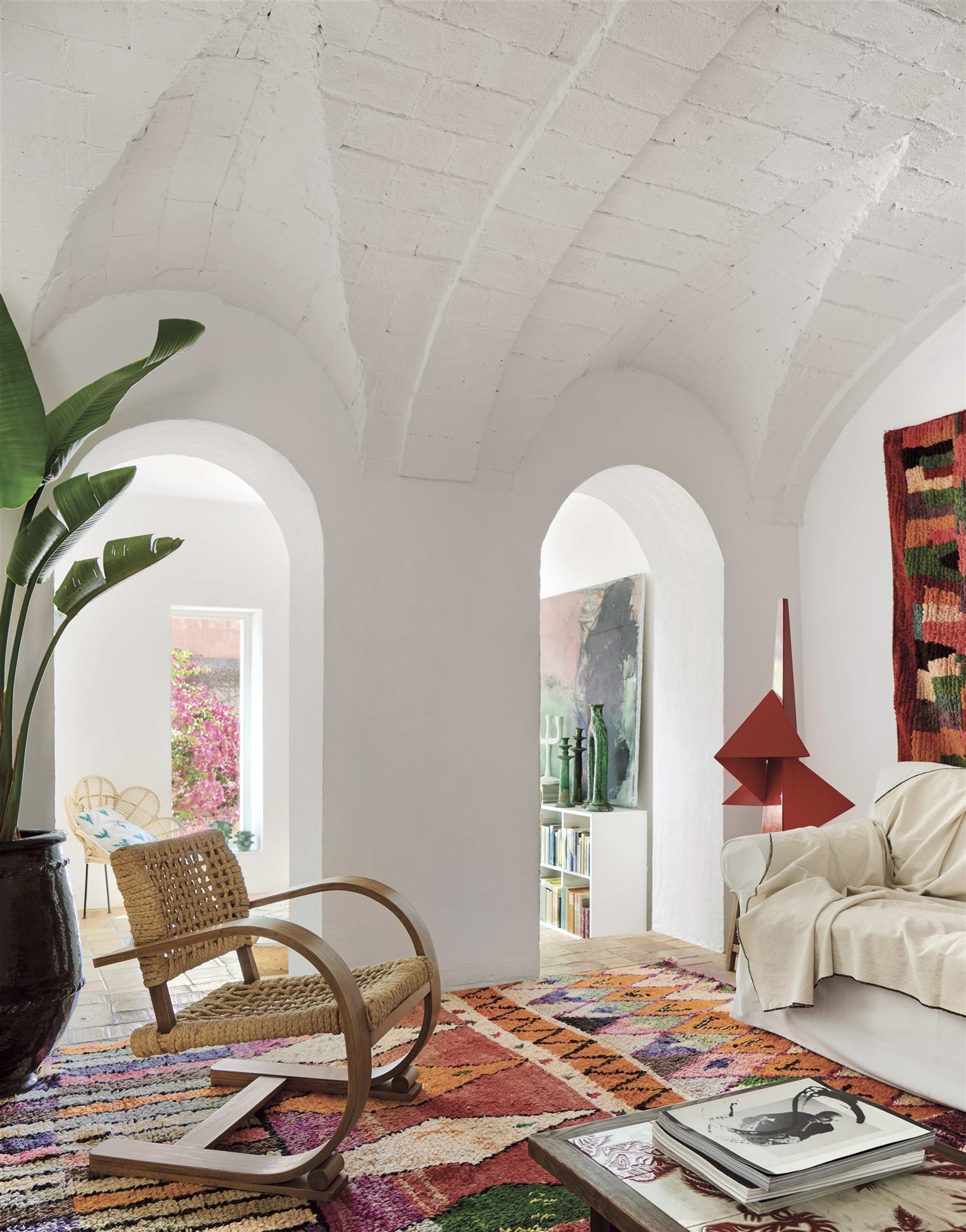salón ecléctico alfombra marroquí, butaca de mimbre, sofá blanco 