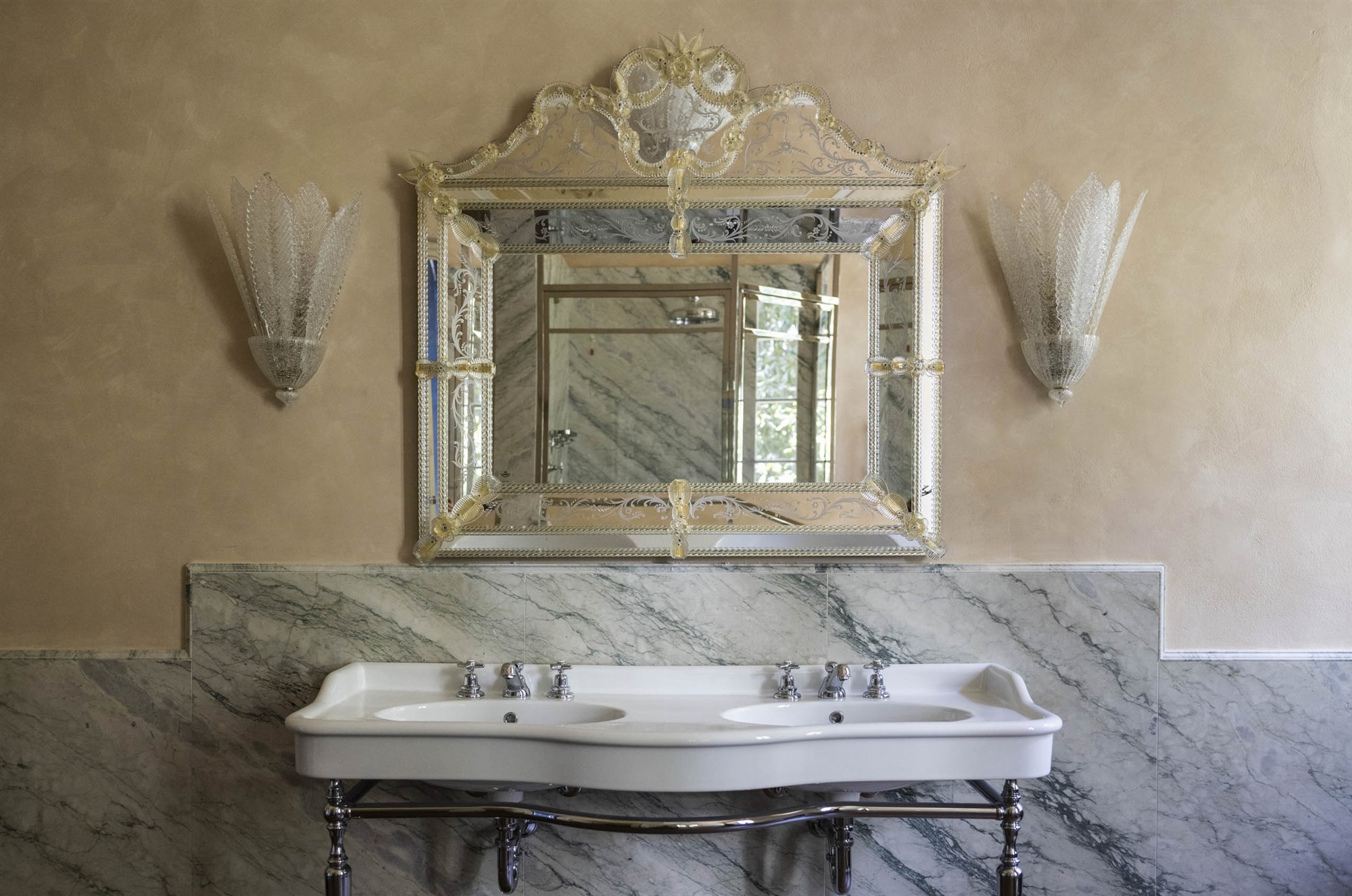 baño clásico con lavabo de mármol, lámpara art deco y espejo dorado