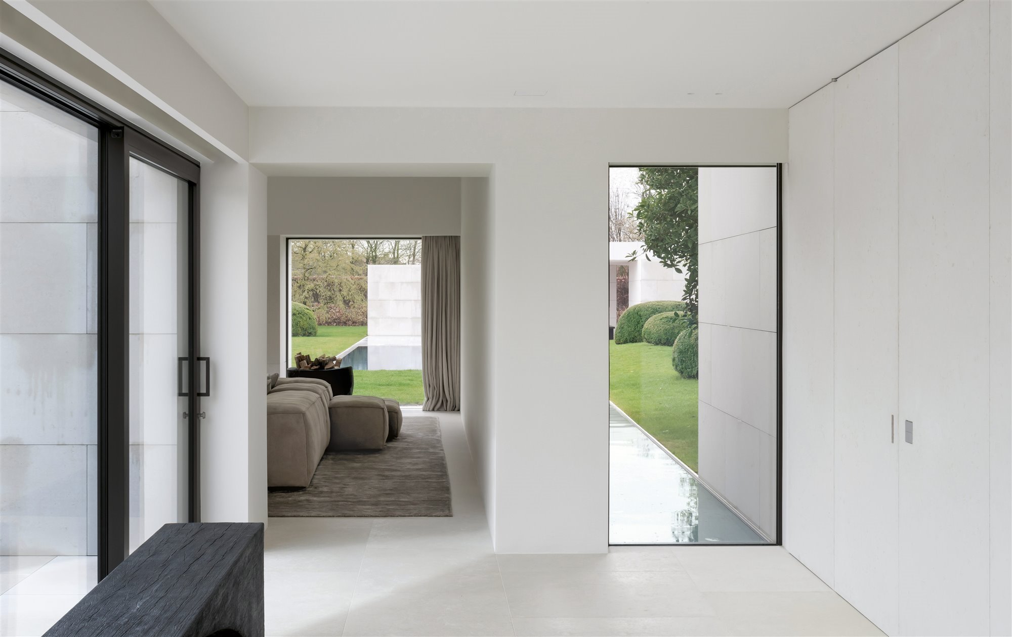casa minimalista con vestíbulo blanco, salón beige y puertas al jardín
