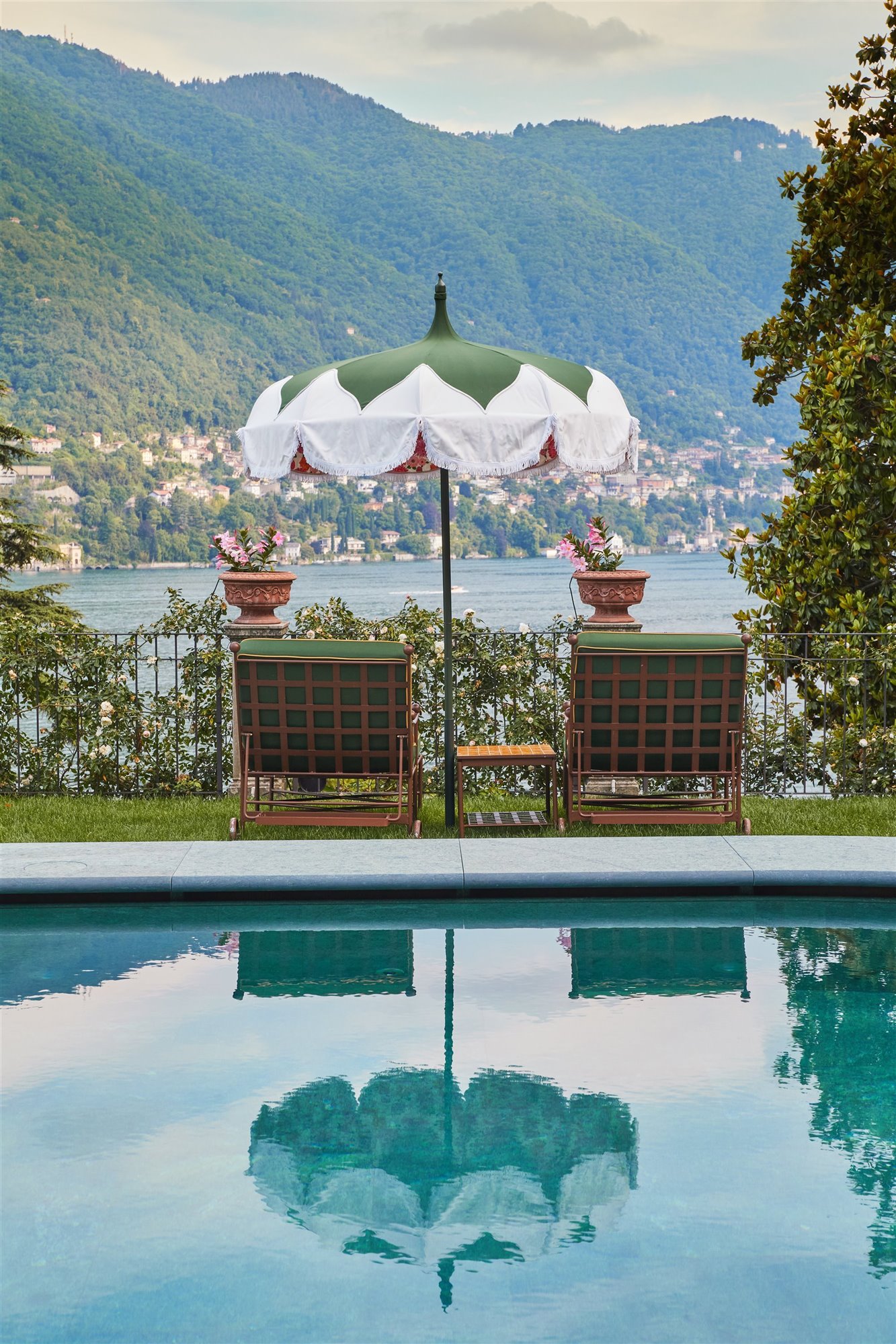 piscina con sombrilla verde y hamacas con vistas al mar