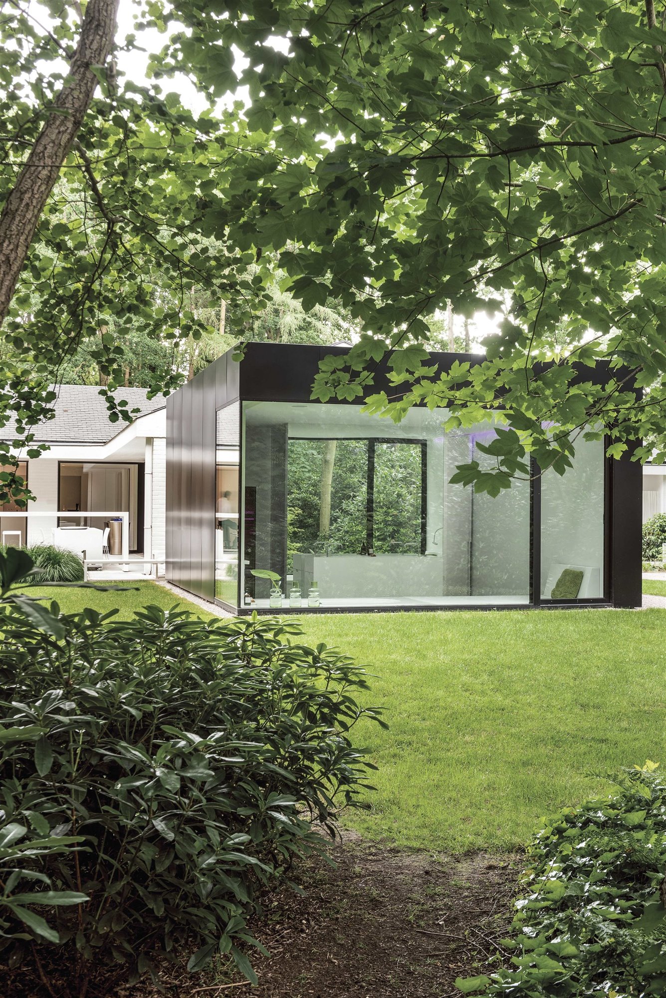 casa caja negra con jardín y fachada acristalada