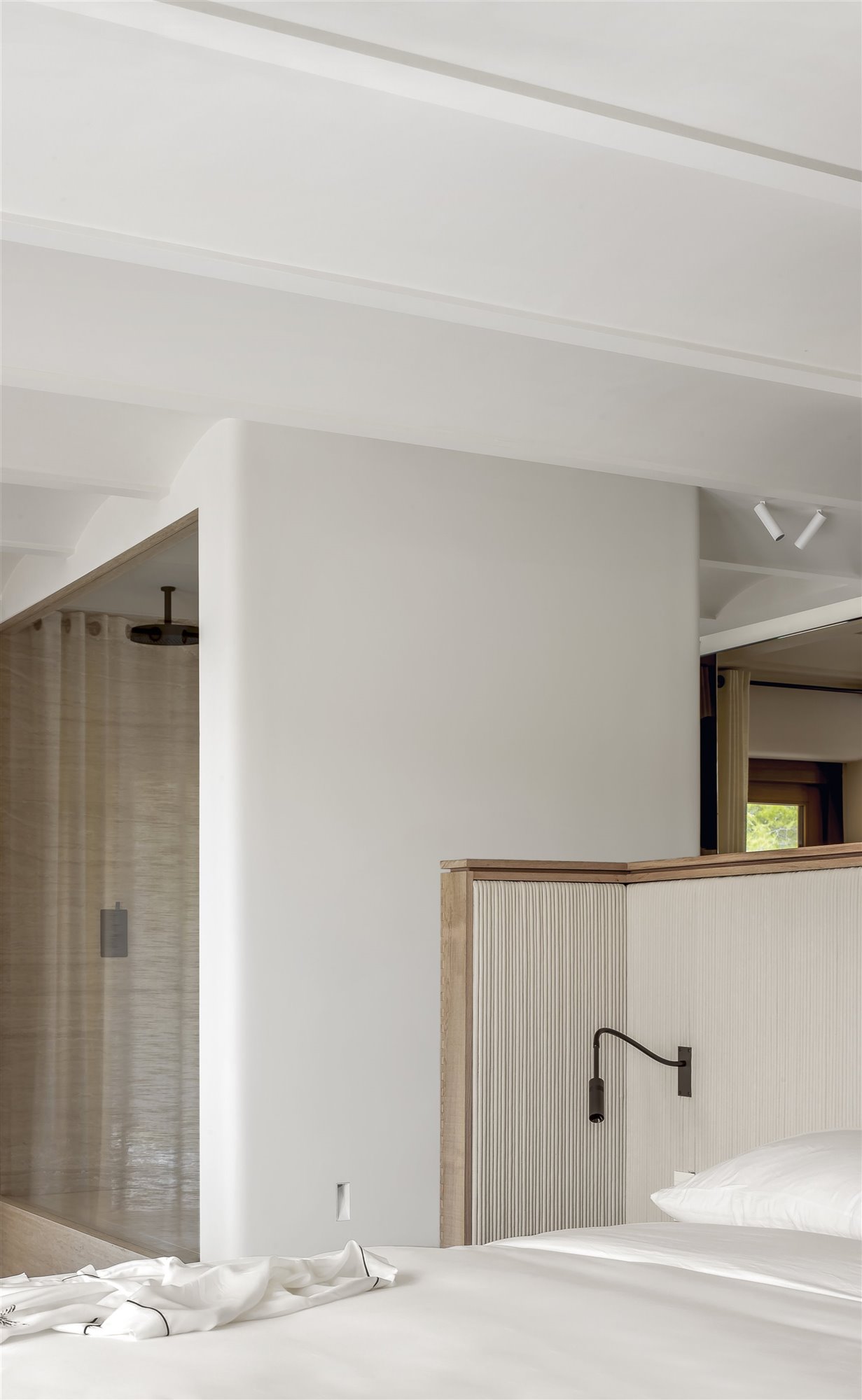 dormitorio blanco con baño integrado, cama con cabecero de madera y tela