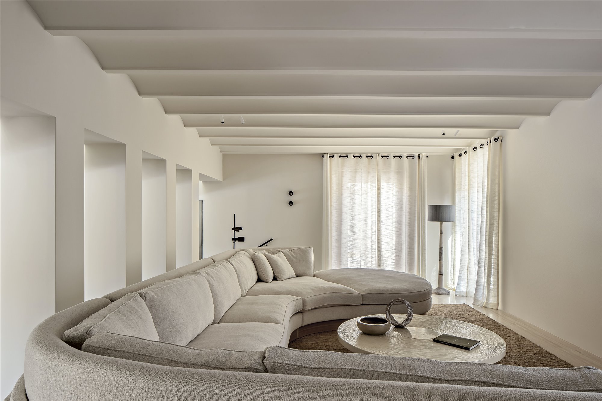salón blanco con sofá de gran medida gris y mesa de café redonda