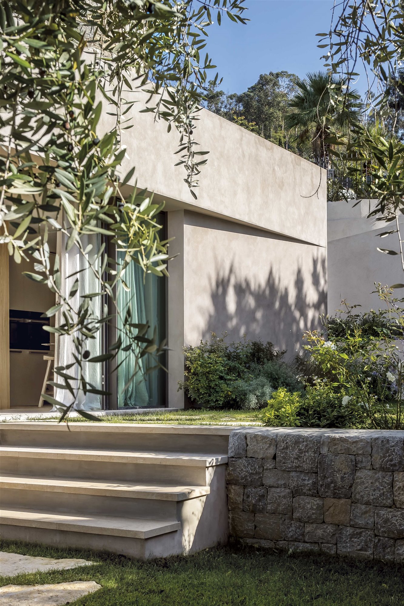 casa brutalista con jardín y puertas de cristal correderas