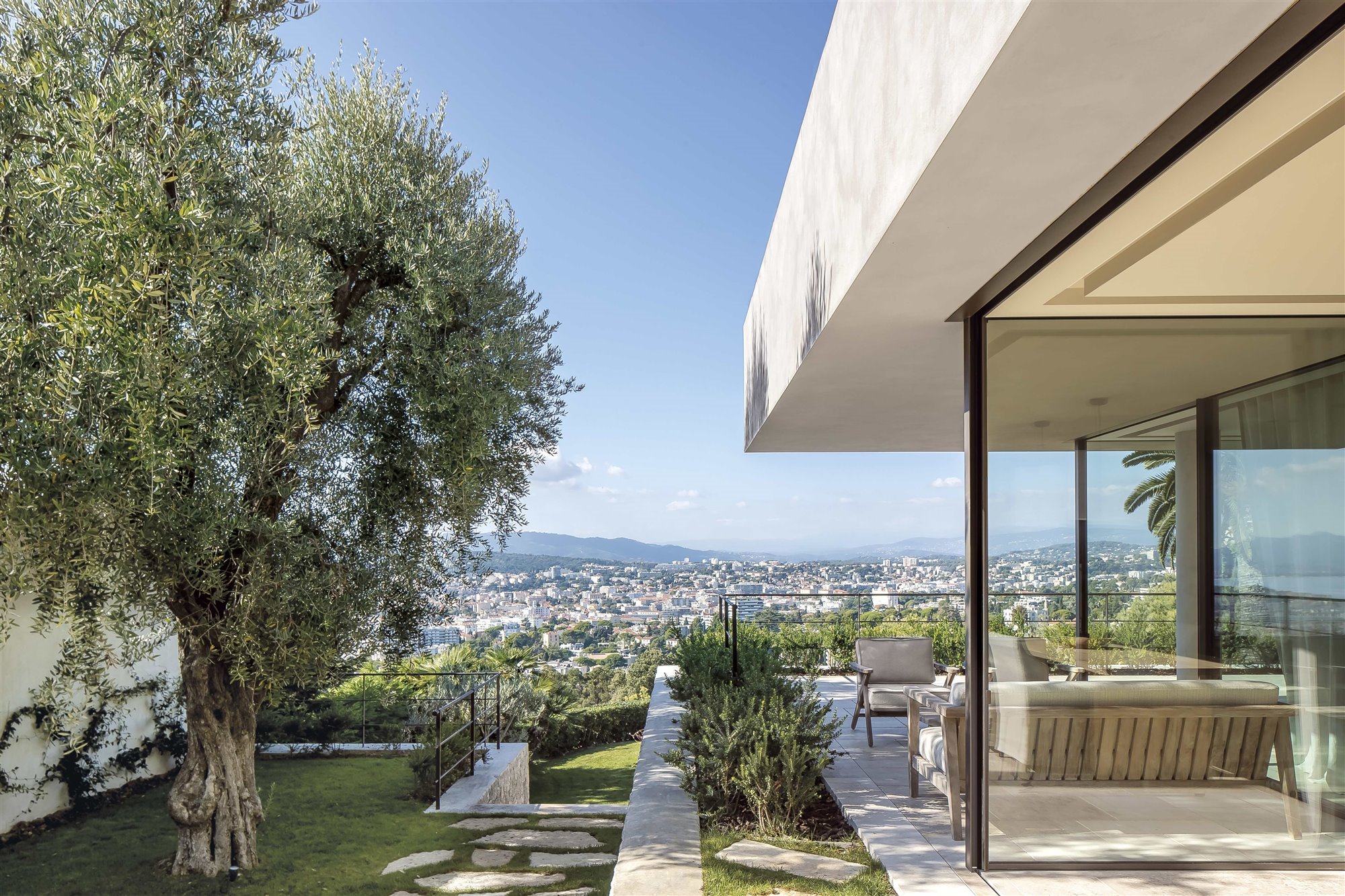 casa brutalista con puertas de cristal y jardín y terraza con muebles de exterior