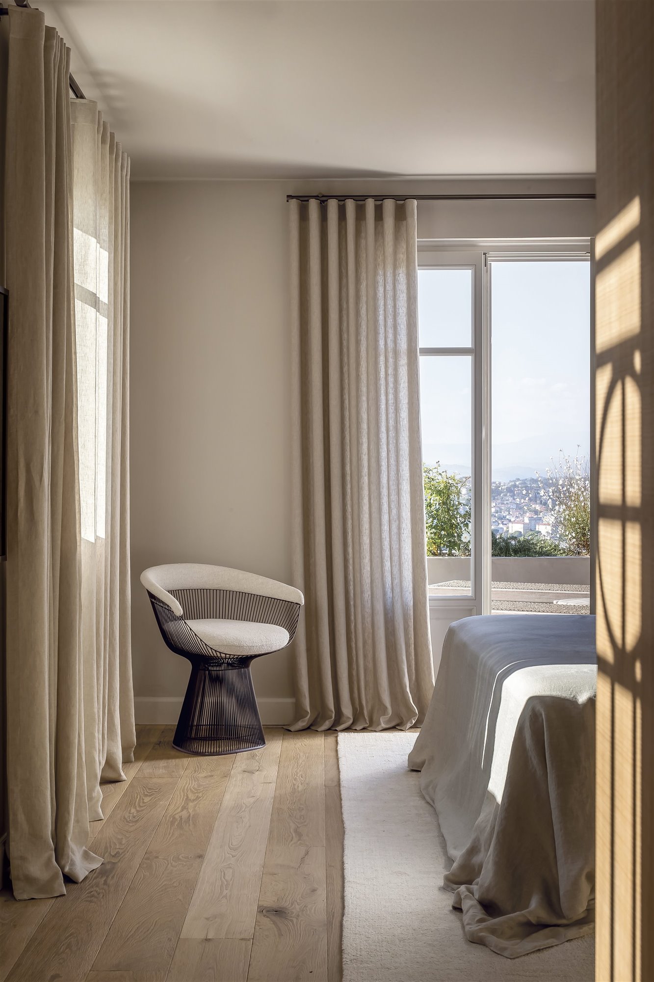 dormitorio rústico minimalista con balcón, sillón blanco y cortinas beige