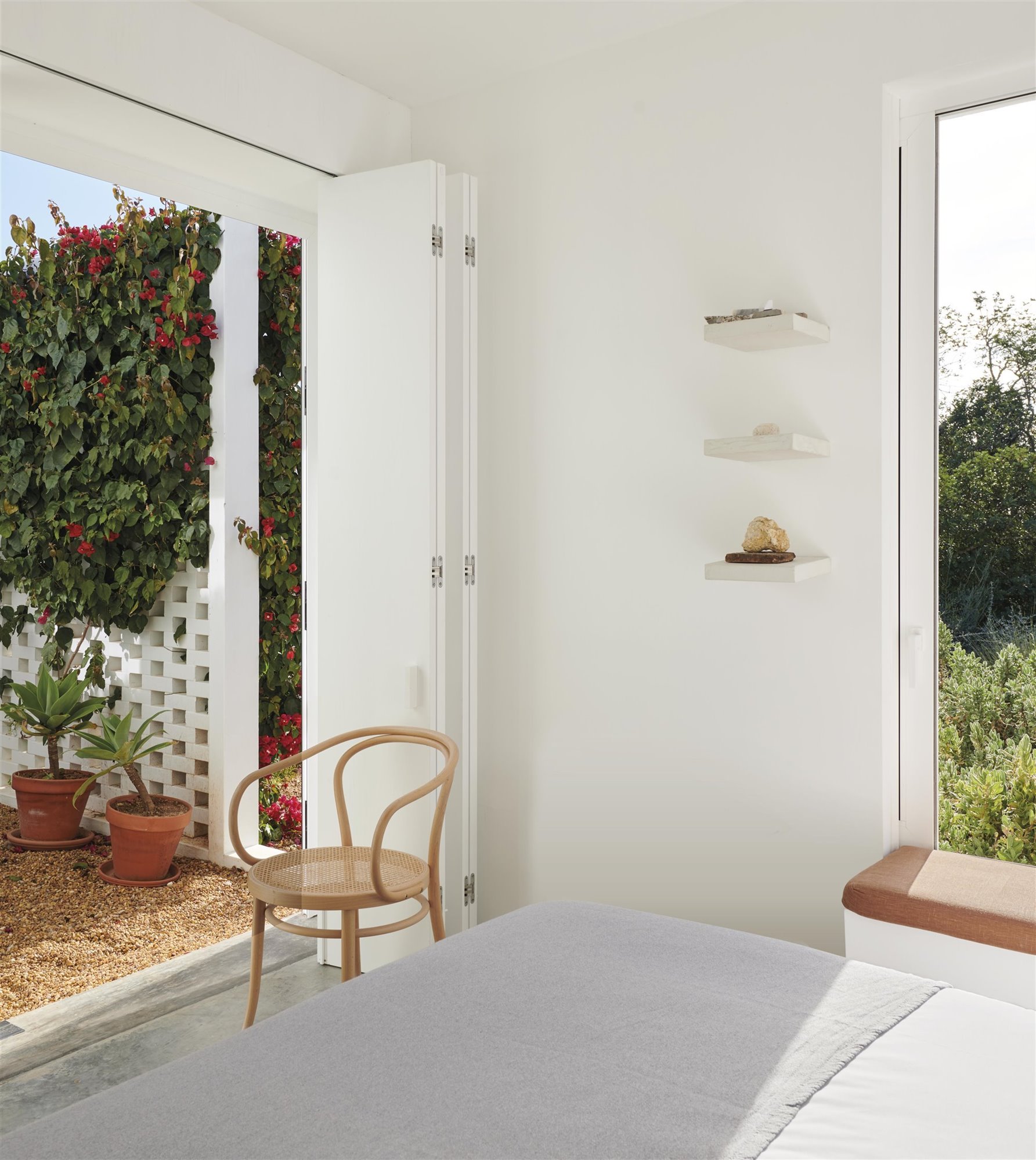 habitación blanca con silla de madera y patio rústico