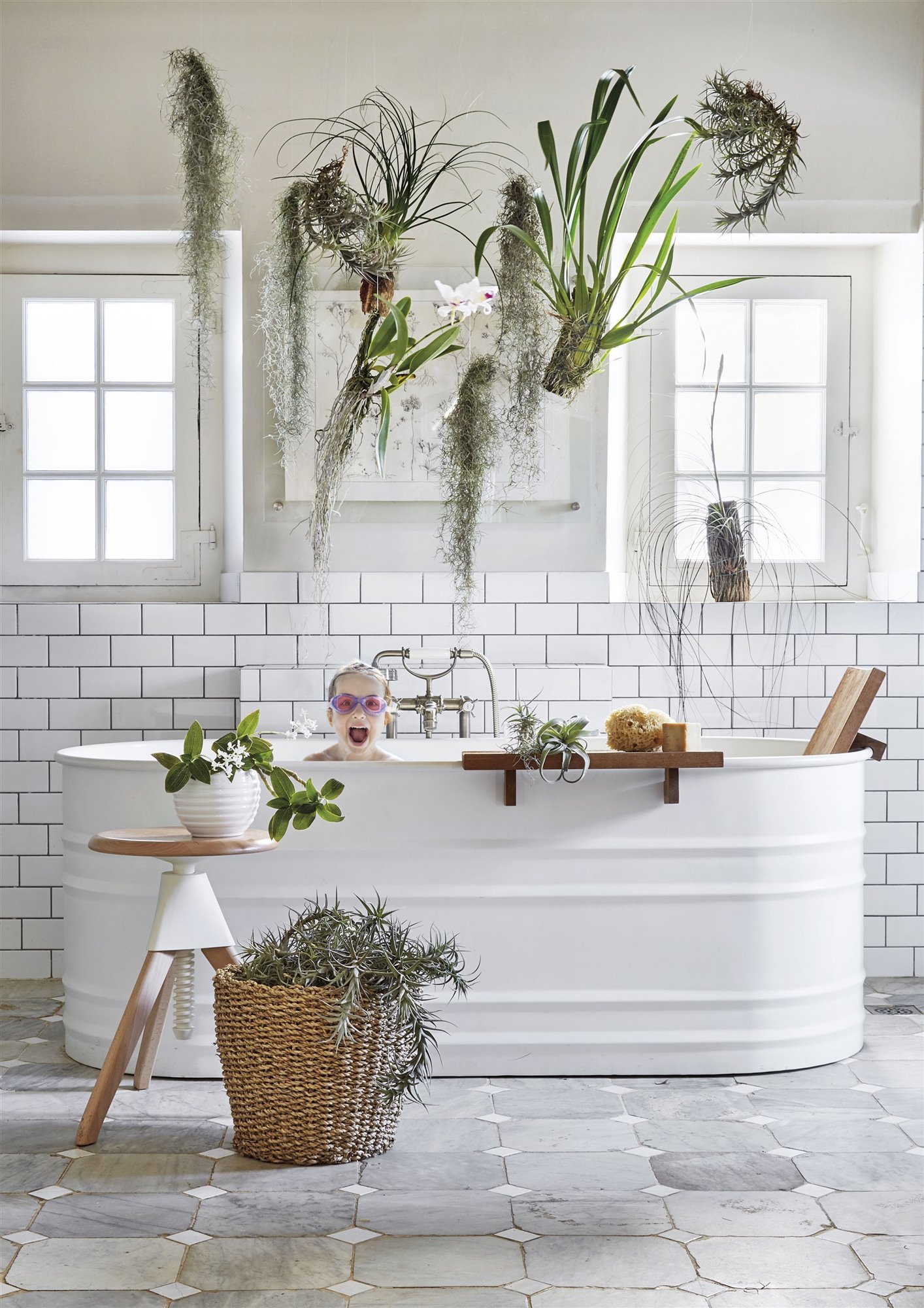 baño blanco con bañera, plantas, cesto de mimbre y taburete de madera