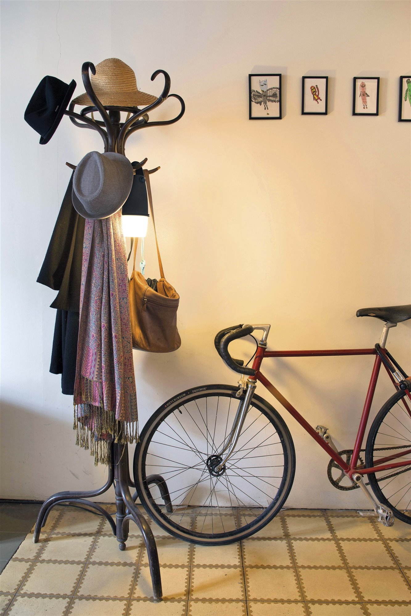 recibidor con perchero con sombreros y luz y una bicicleta