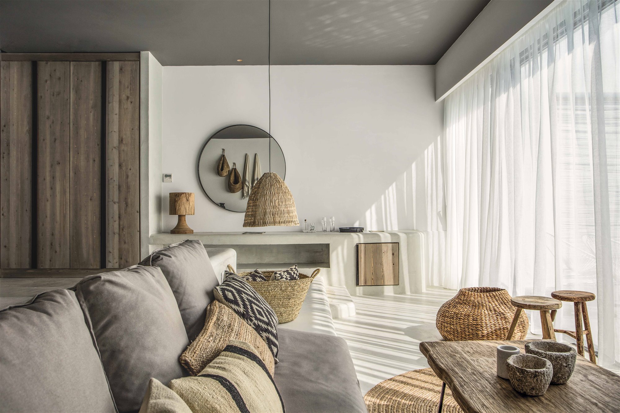 salón boho con sofá gris, muebles de madera y mimbre