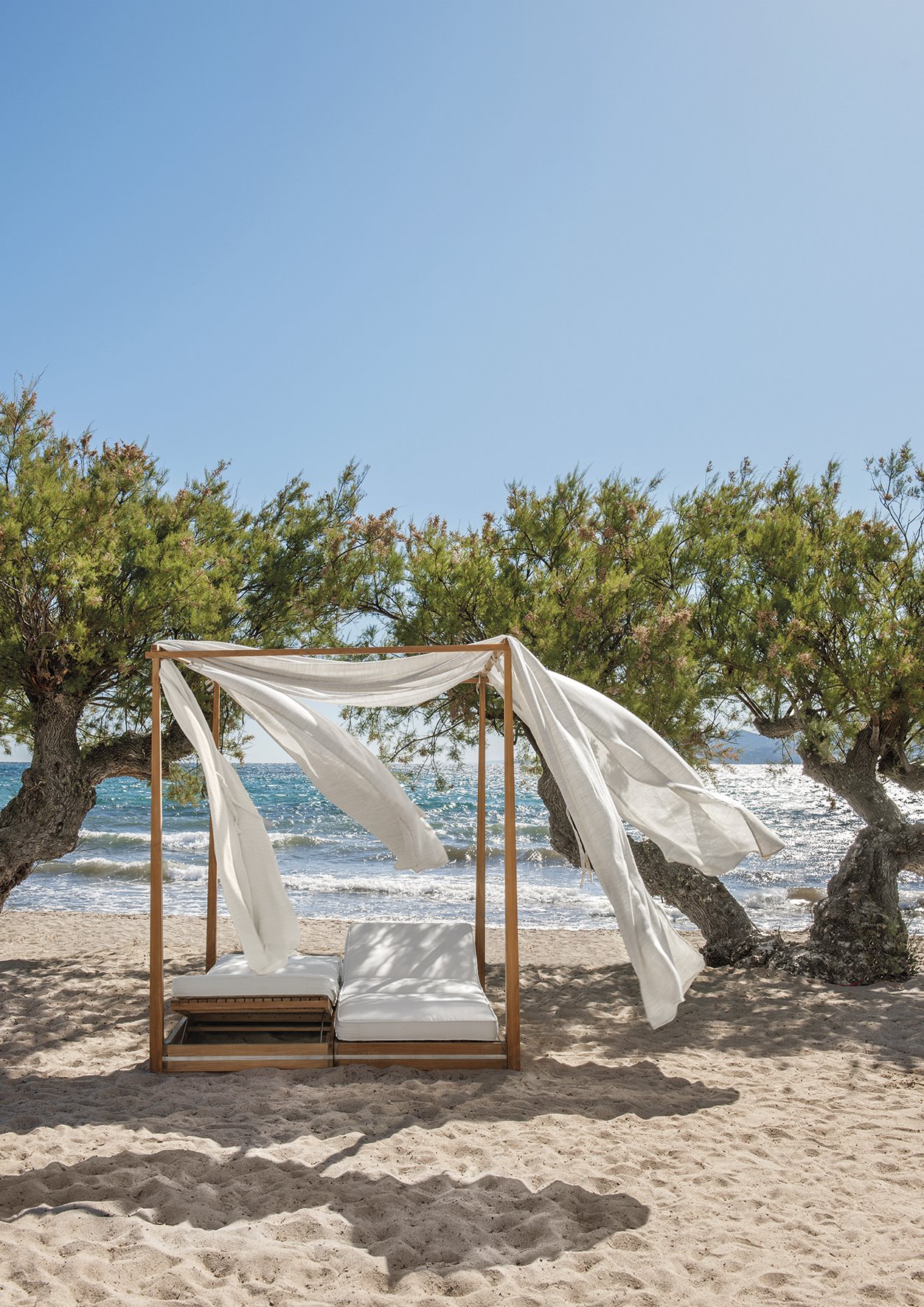 cama de madera con dosel blanco en la playa