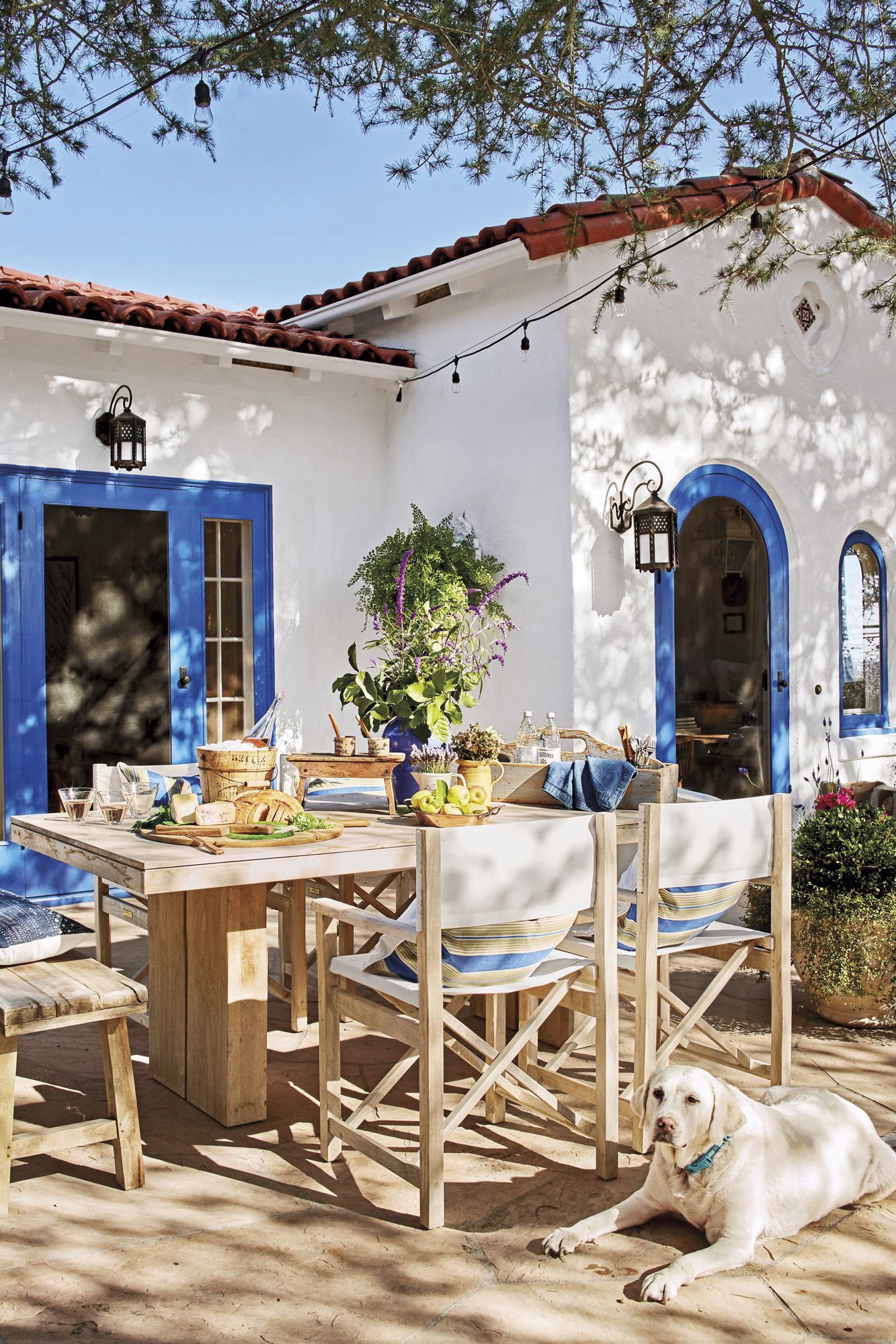 casa mediterránea azul y blanca con patio y mesa de comedor con sillas blancas 