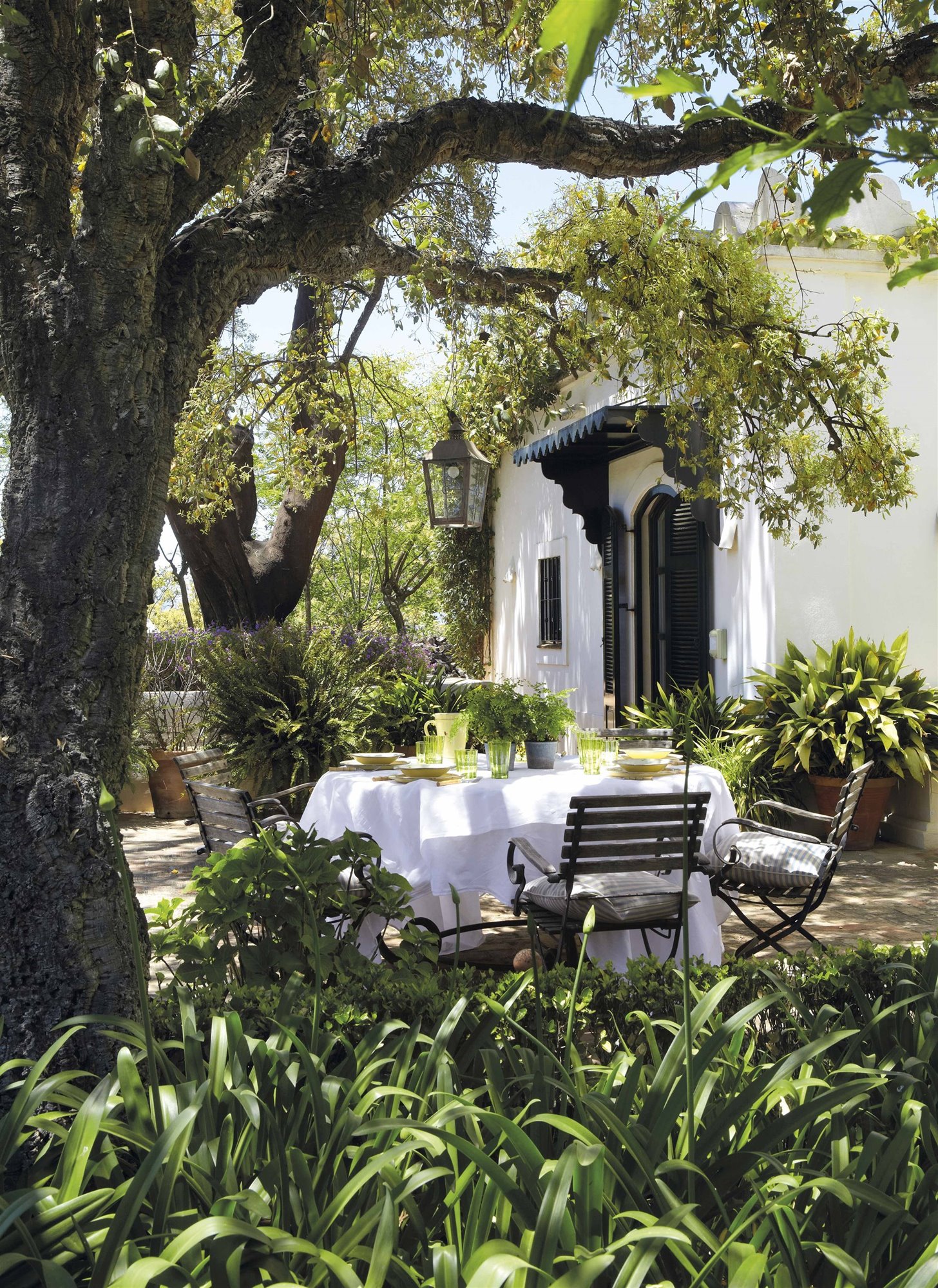 jardín en una casa de campo romántica con mesa de desayuno y mantel blanco