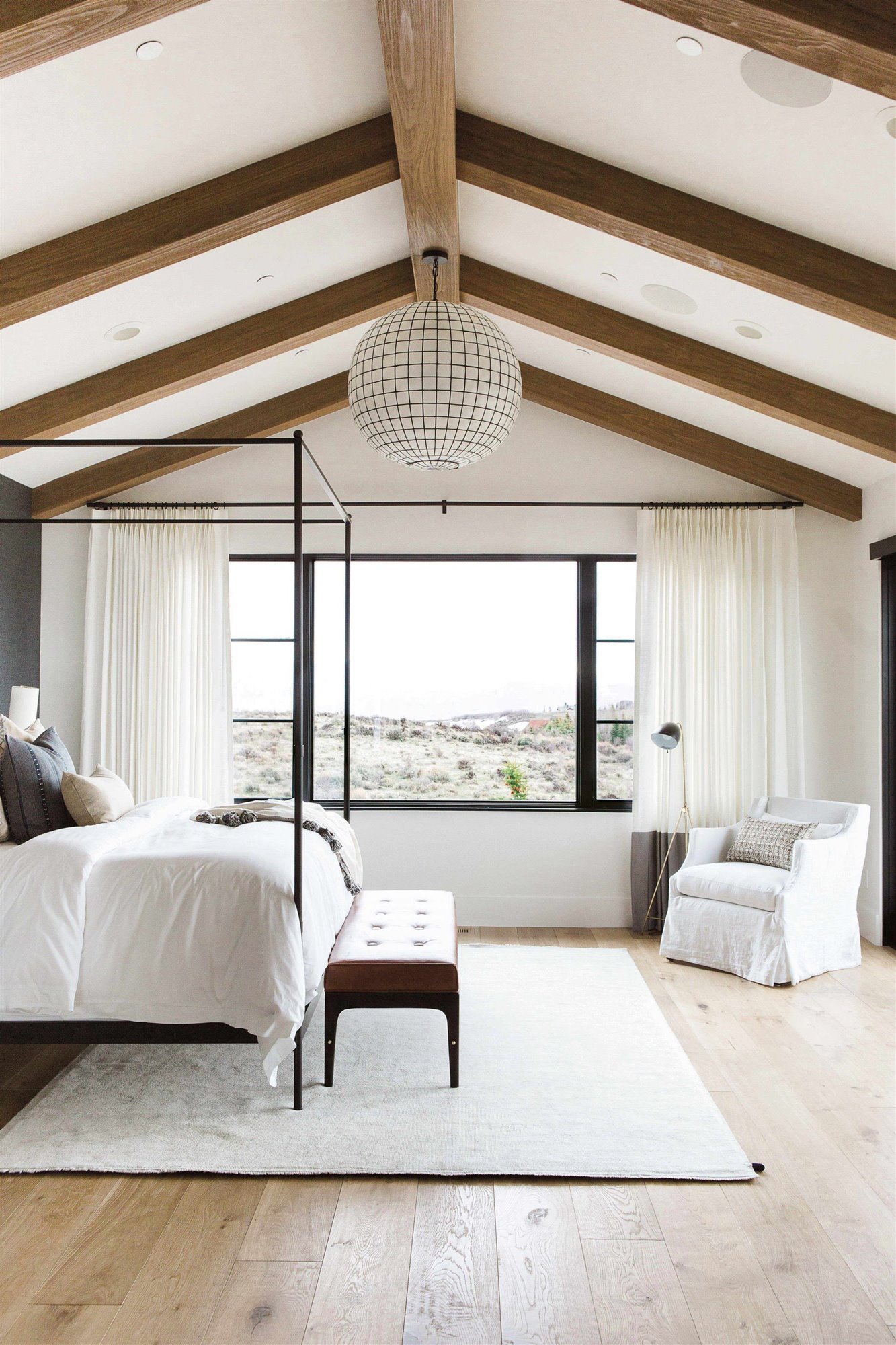 dormitorio casa de campo minimalista con techo de vigas de madera y cama con dosel negro