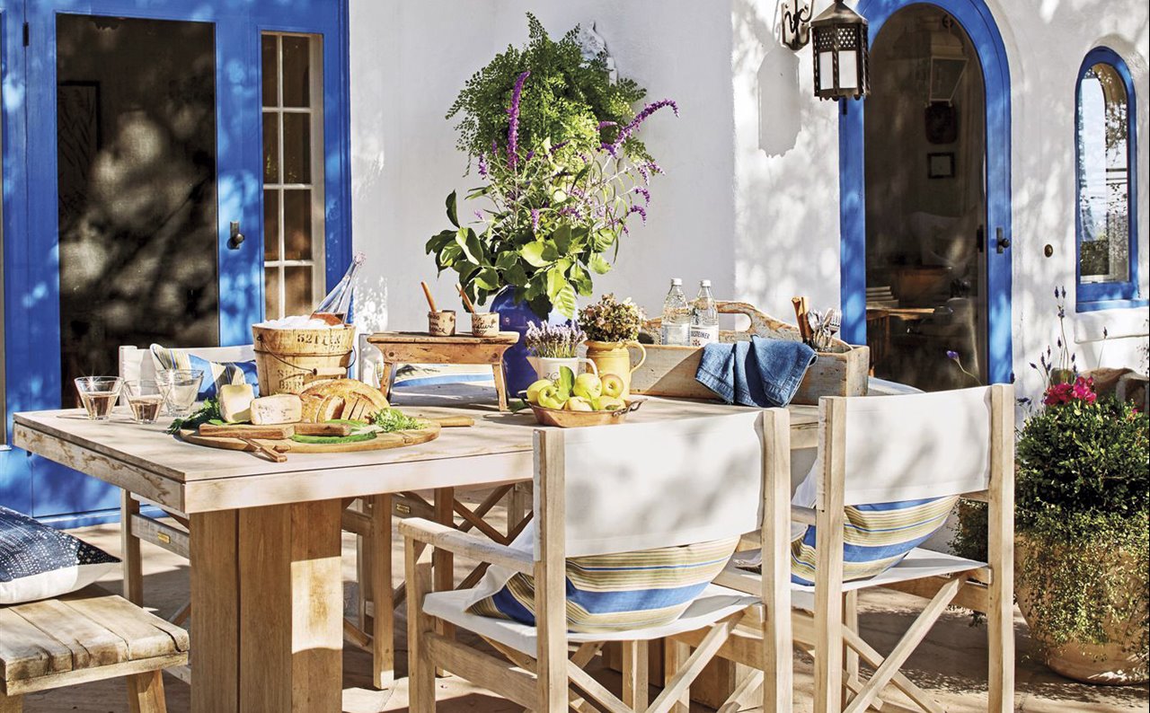 casa mediterránea azul y blanca con patio y mesa de comedor con sillas blancas 