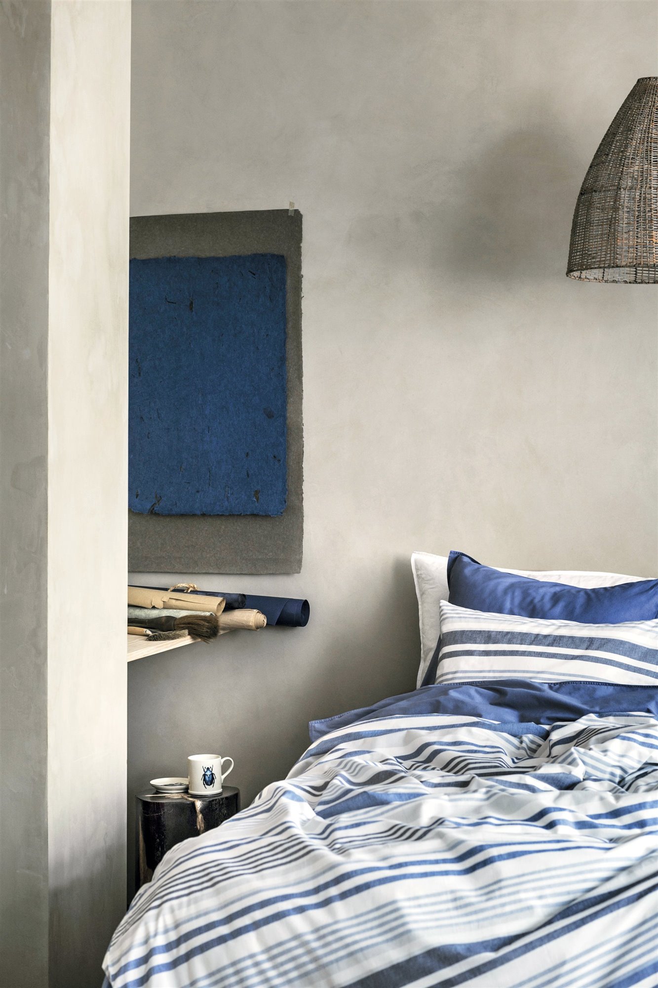 dormitorio gris y azul con sábanas de rayas marineras