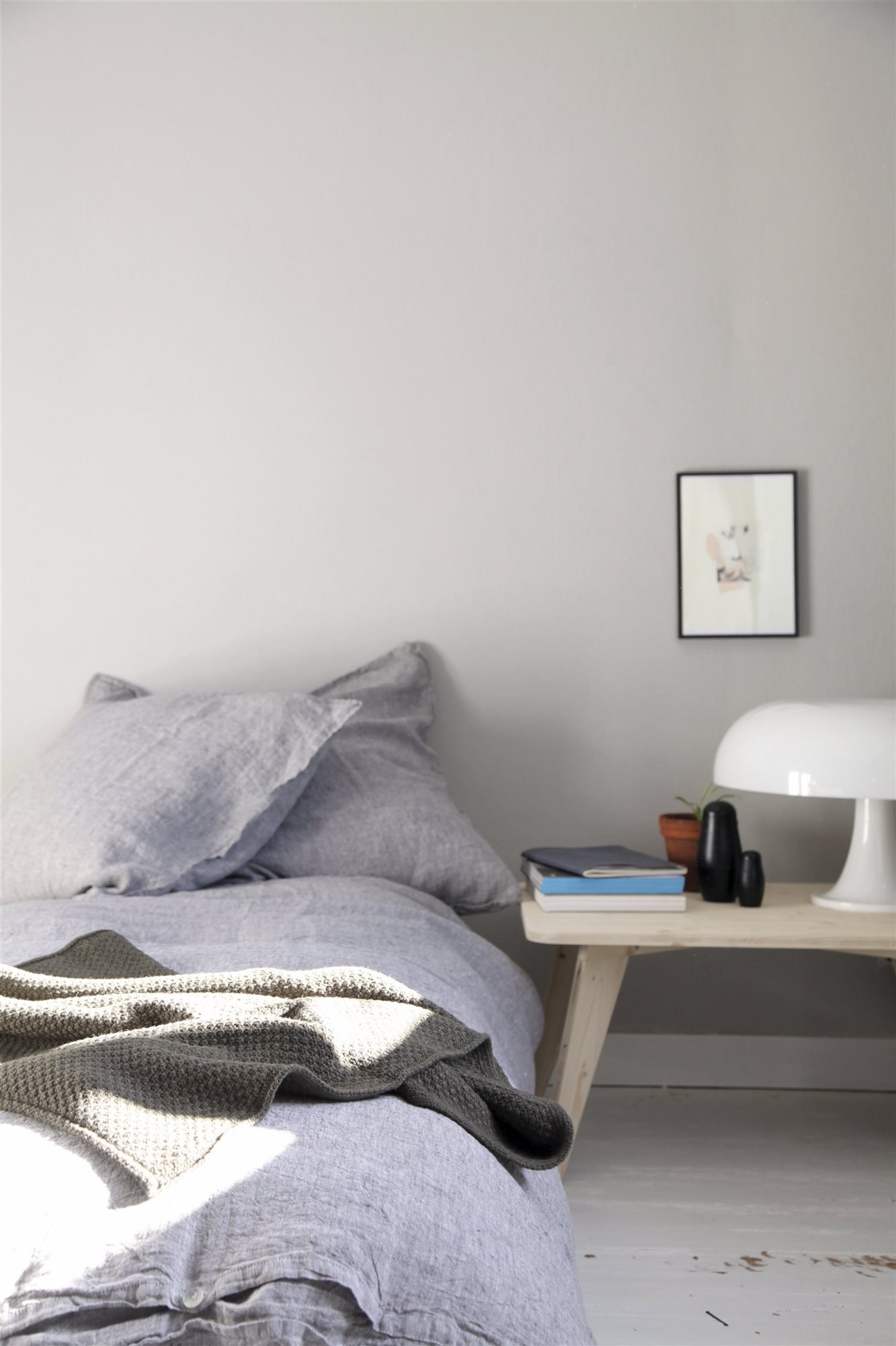 dormitorio minimalista con cama lavanda, banco de madera y lámpara seta blanca
