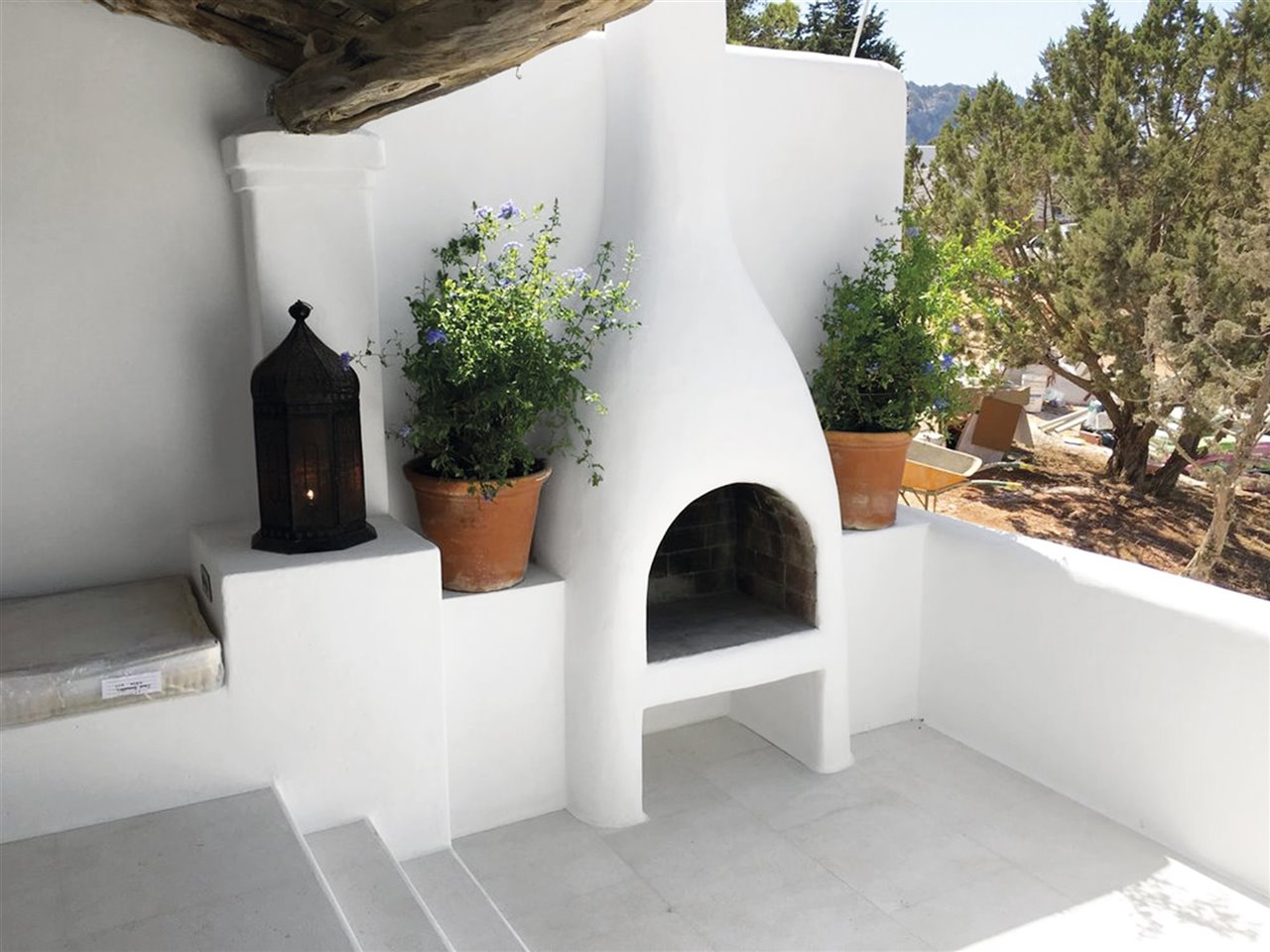 barbacoa de obra de ladrillo blanco con macetas de plantas