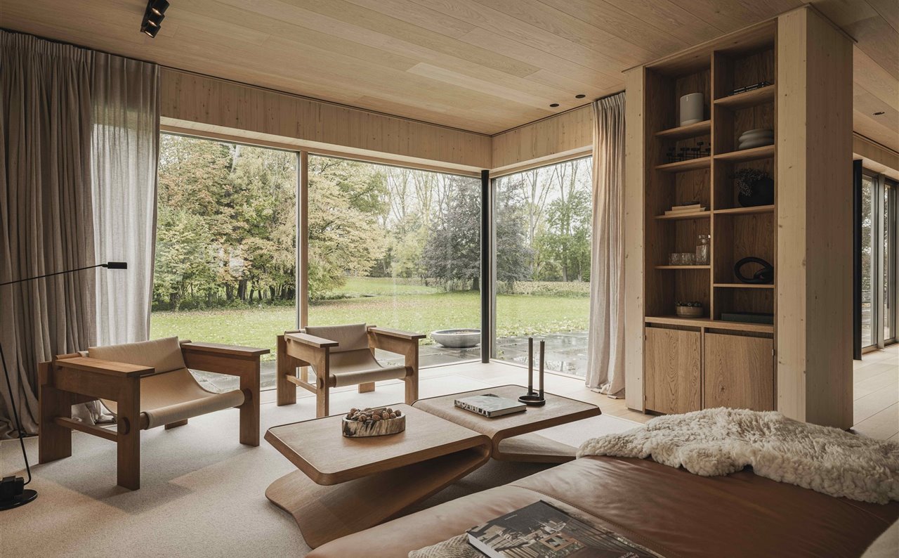 El salón, con vistas al bosque, está decorado con muebles de madera de roble de edición limitada, concretamente con una mesa de centro y butacas tapizadas en lino, terciopelo u otros materiales, todo de los portugueses Studio HAOS.