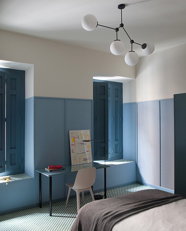 Dormitorio con suelo damero, cerramientos de madera azules, pesa de trabajo