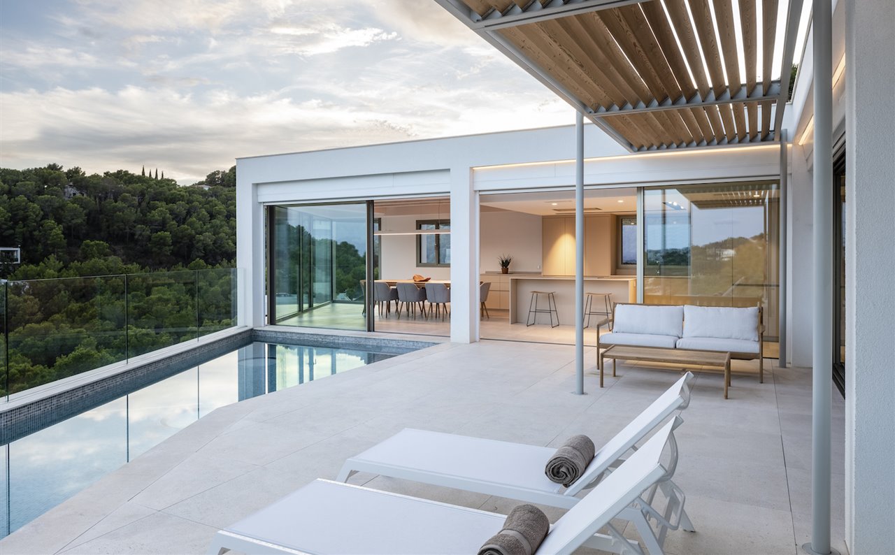 La zona de día, conectada con la terraza y la piscina, se ubica en el nivel superior. Carpintería corredera Line, de Home of Horizon