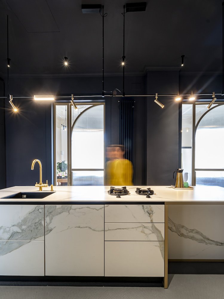 persona-cocinando-en-isla-de-cocina-efecto-marmol-con-muebles-altos-empotrados-de-arredo-cometa-architects