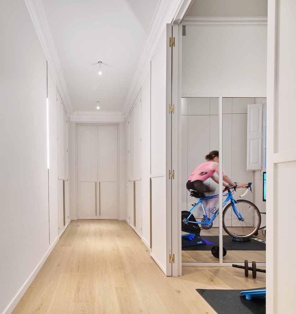 persona-entrenando-con-bicicleta-pasillo-habitacion-con-espejo-bicleta-Reforma-Cometa-Architects