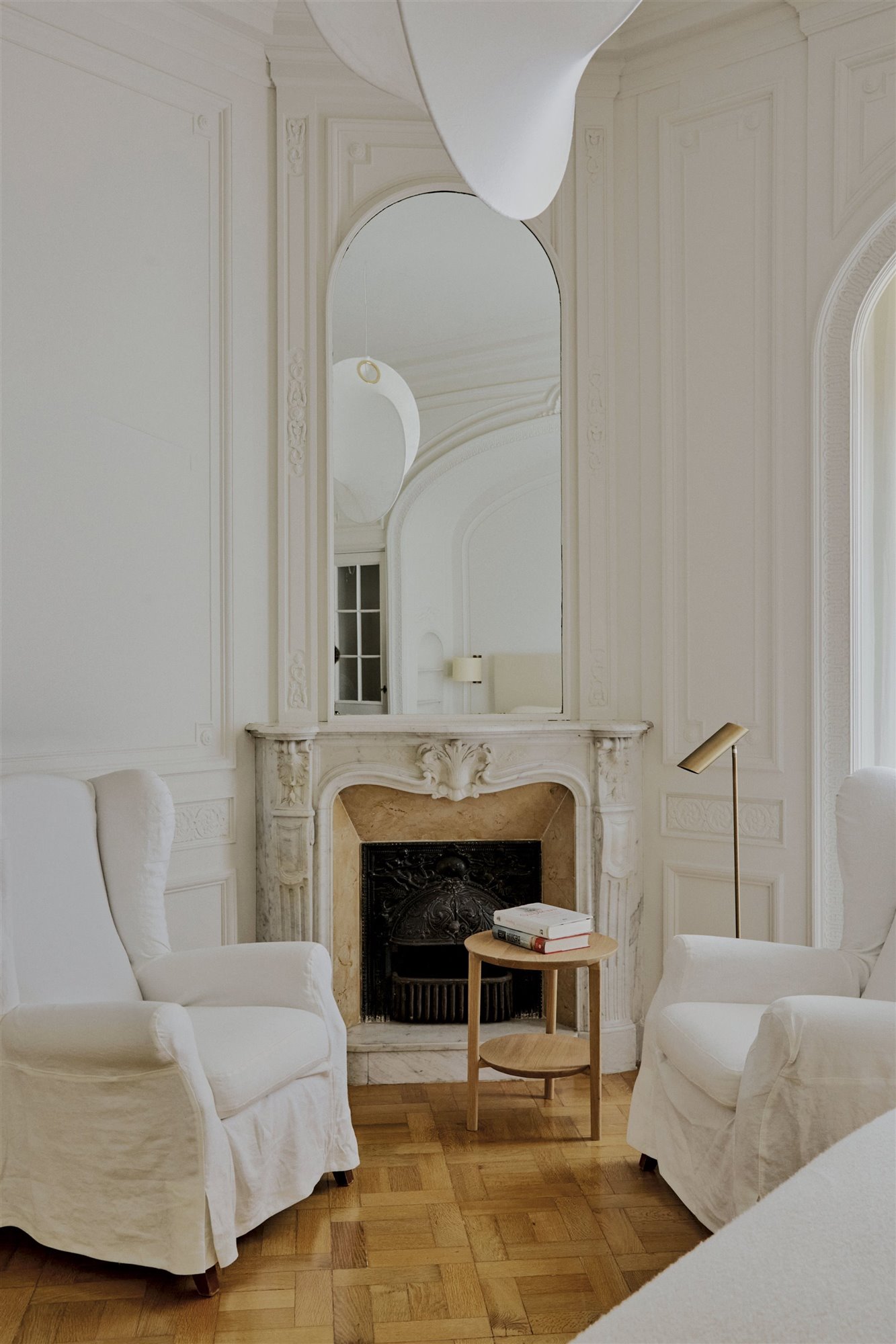 salón clásico blanco con chimenea espejo y butacas