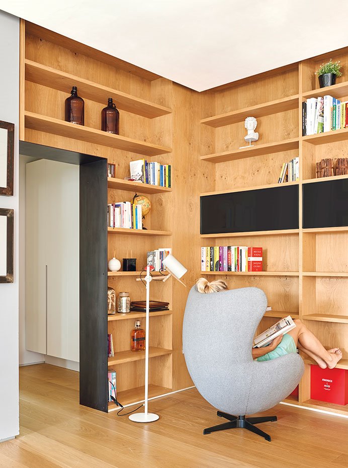 Estantería de madera de roble, a medida. Butaca Egg, de Arne Jacobsen para Fritz Hansen. Lámpara de pie Scantling, de Mathias Hahn para Marset. Pavimento, de madera de roble.