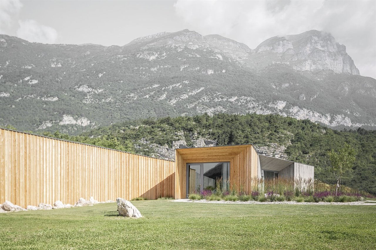 Casa de campo con fachada de madera rodeada de naturaleza en las montañas de Studio Raro