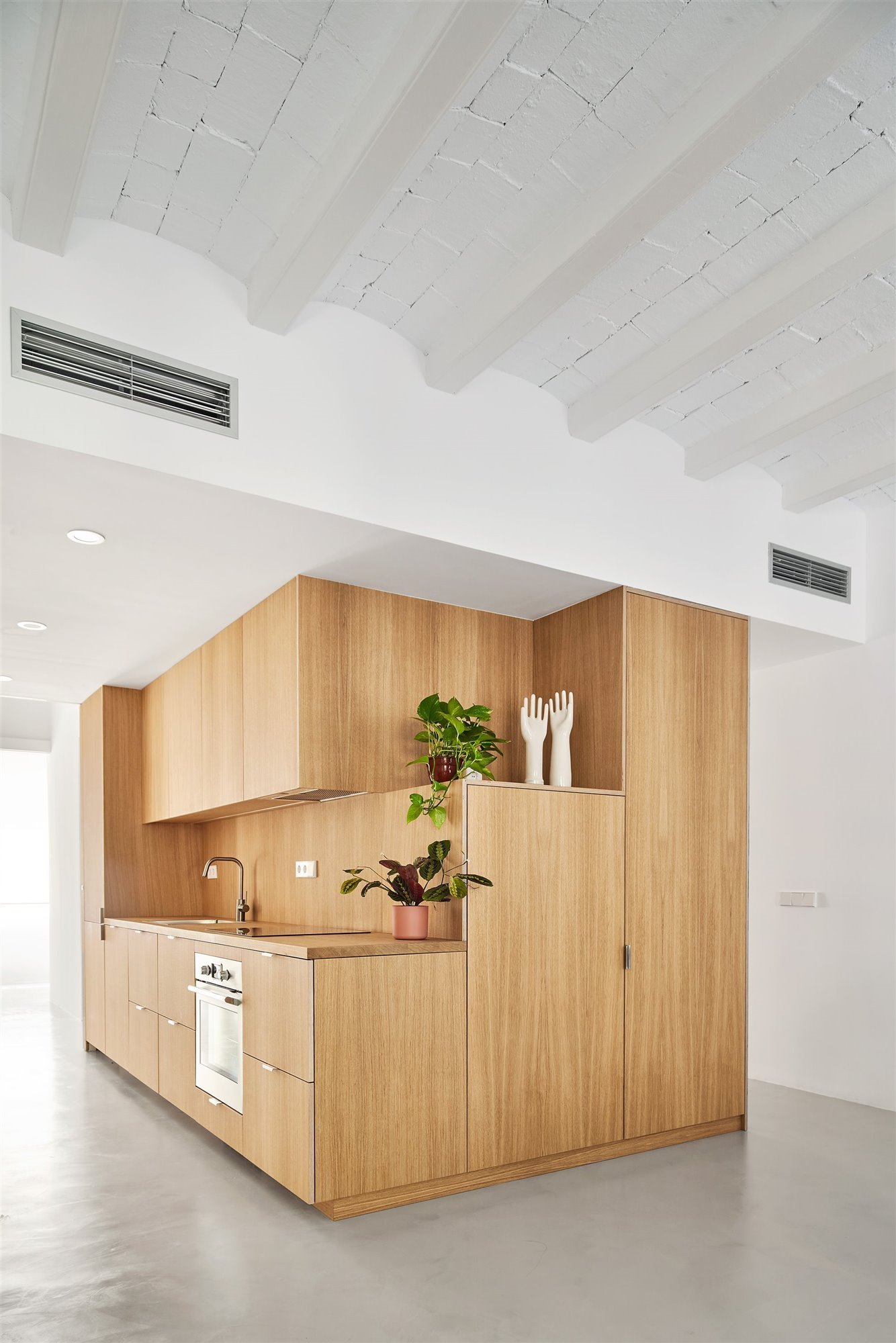 Cocina de madera con frentes lisos y tiradores discretos. 