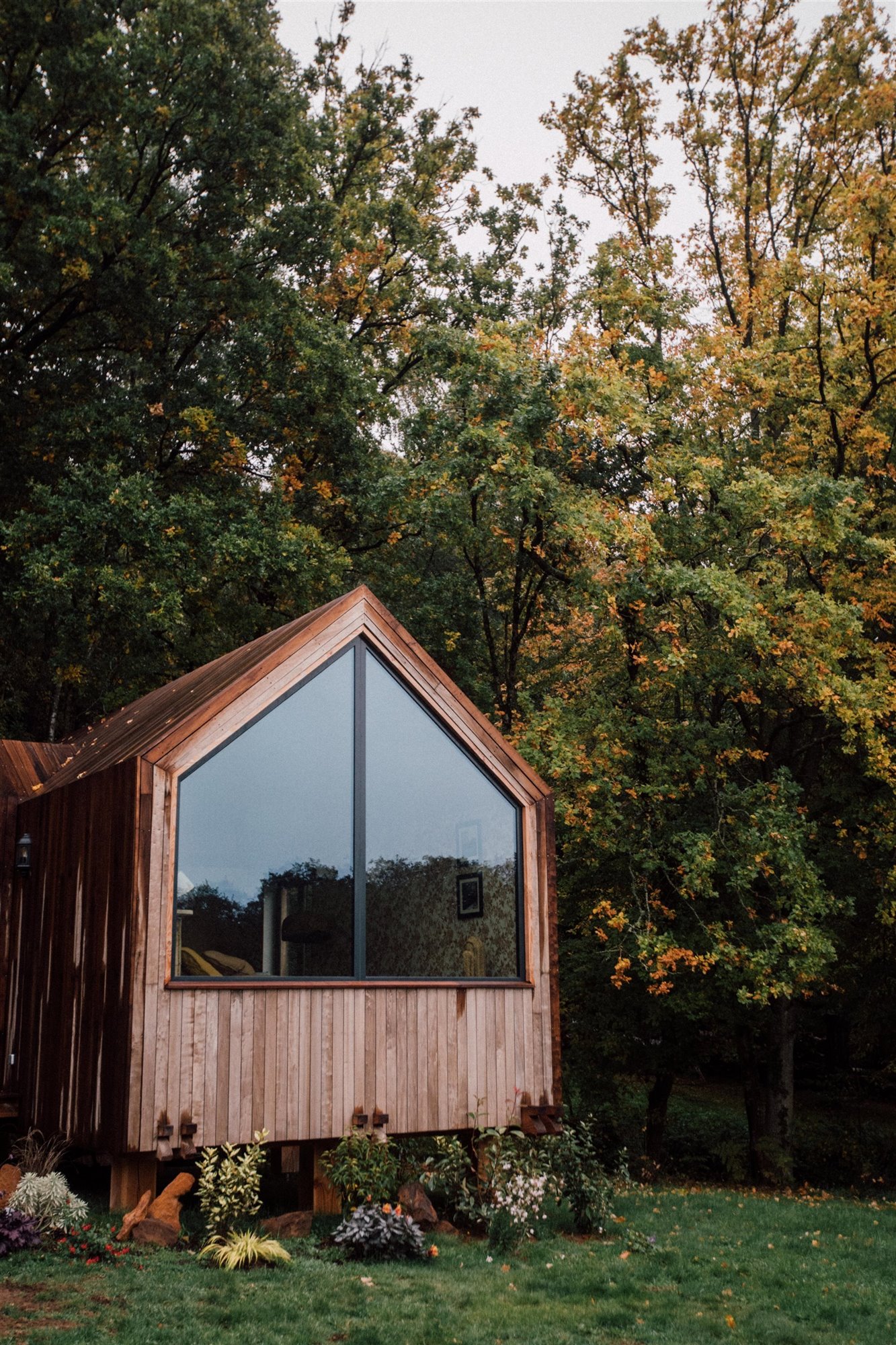 Exterior de una cabaña de madera con gran ventana. 