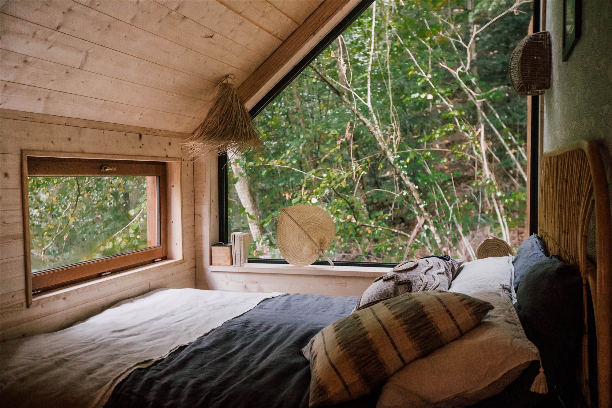 Dormitorio de una cabaña de madera con grandes ventanas. 