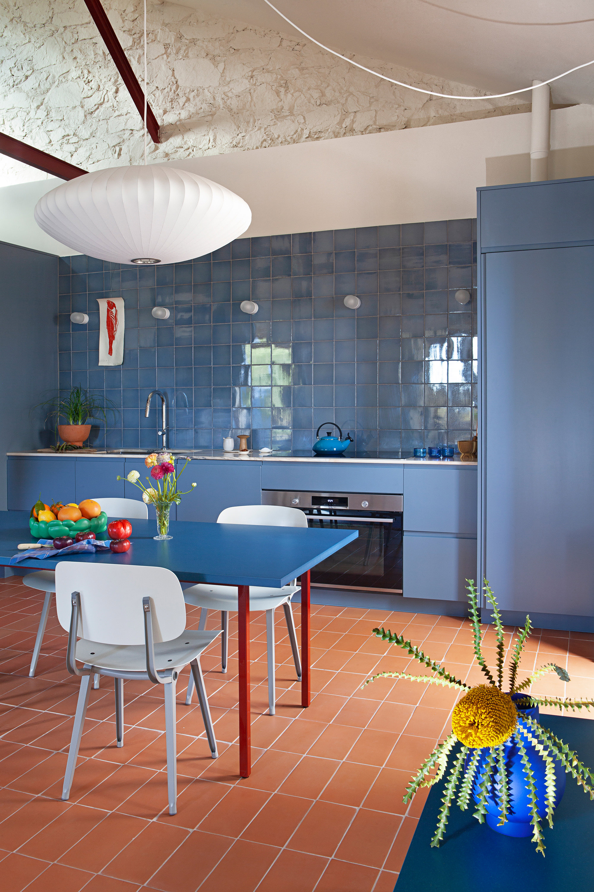El azul de la cocina contrasta con los tonos cálidos de las baldosas de arcilla del suelo.