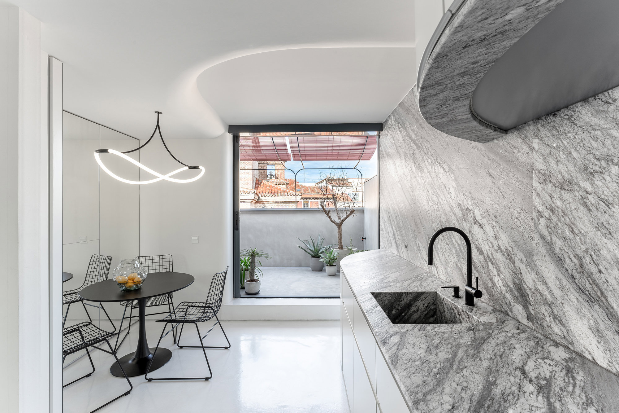 Cocina en granito y comedor con vistas a la terraza con microcemento