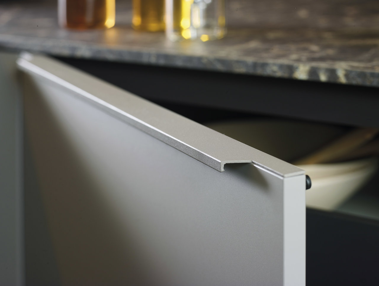 Los tiradores lineales de aluminio se integran discretamente en la parte superior de puertas y cajones
