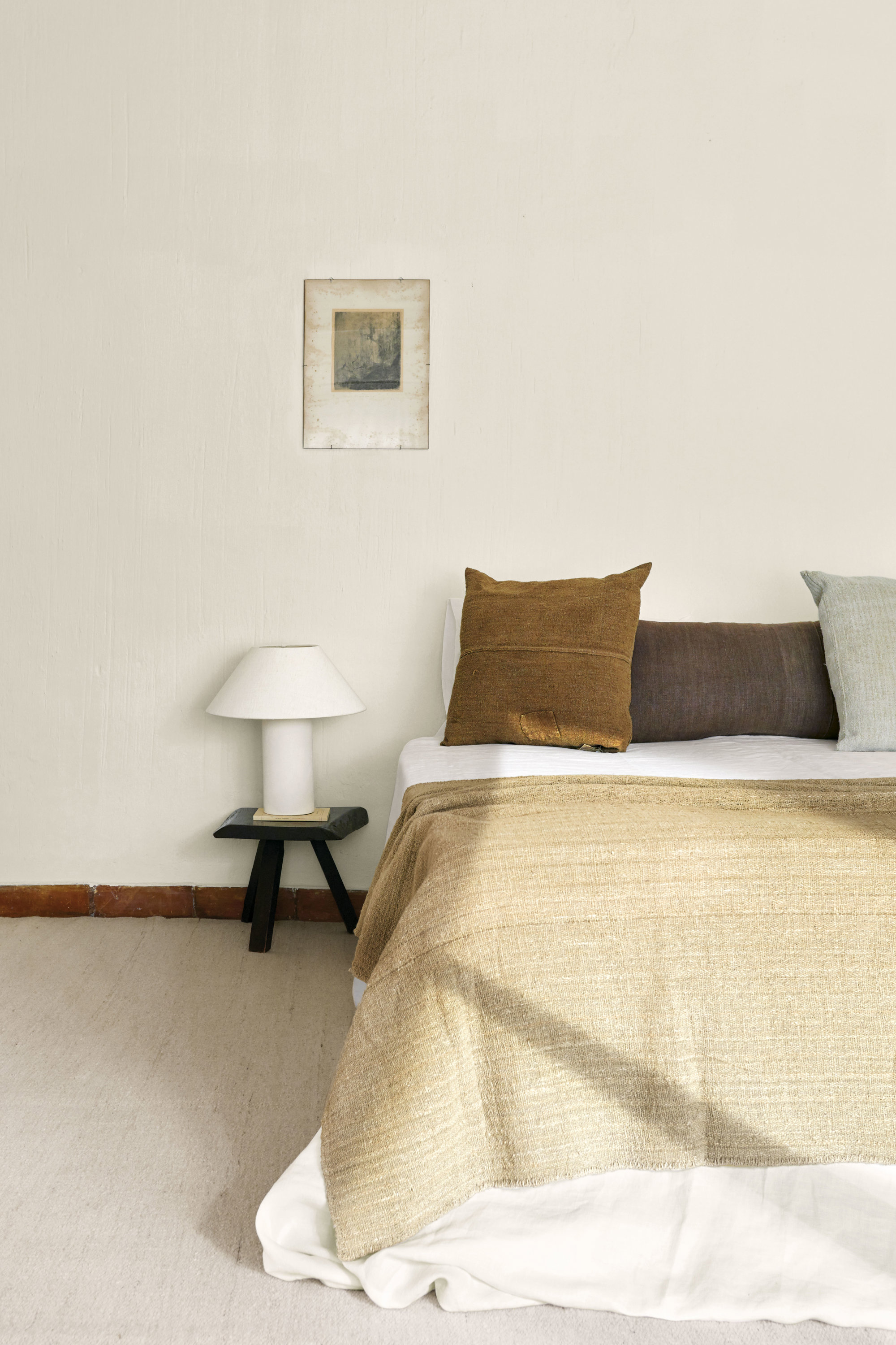 En el dormitorio, taburete de roble suizo del siglo XIX, colchas y cojines, todo de Rue Vintage 74; linos, de Pepe Peñalver, y lámpara, de Zara Home.