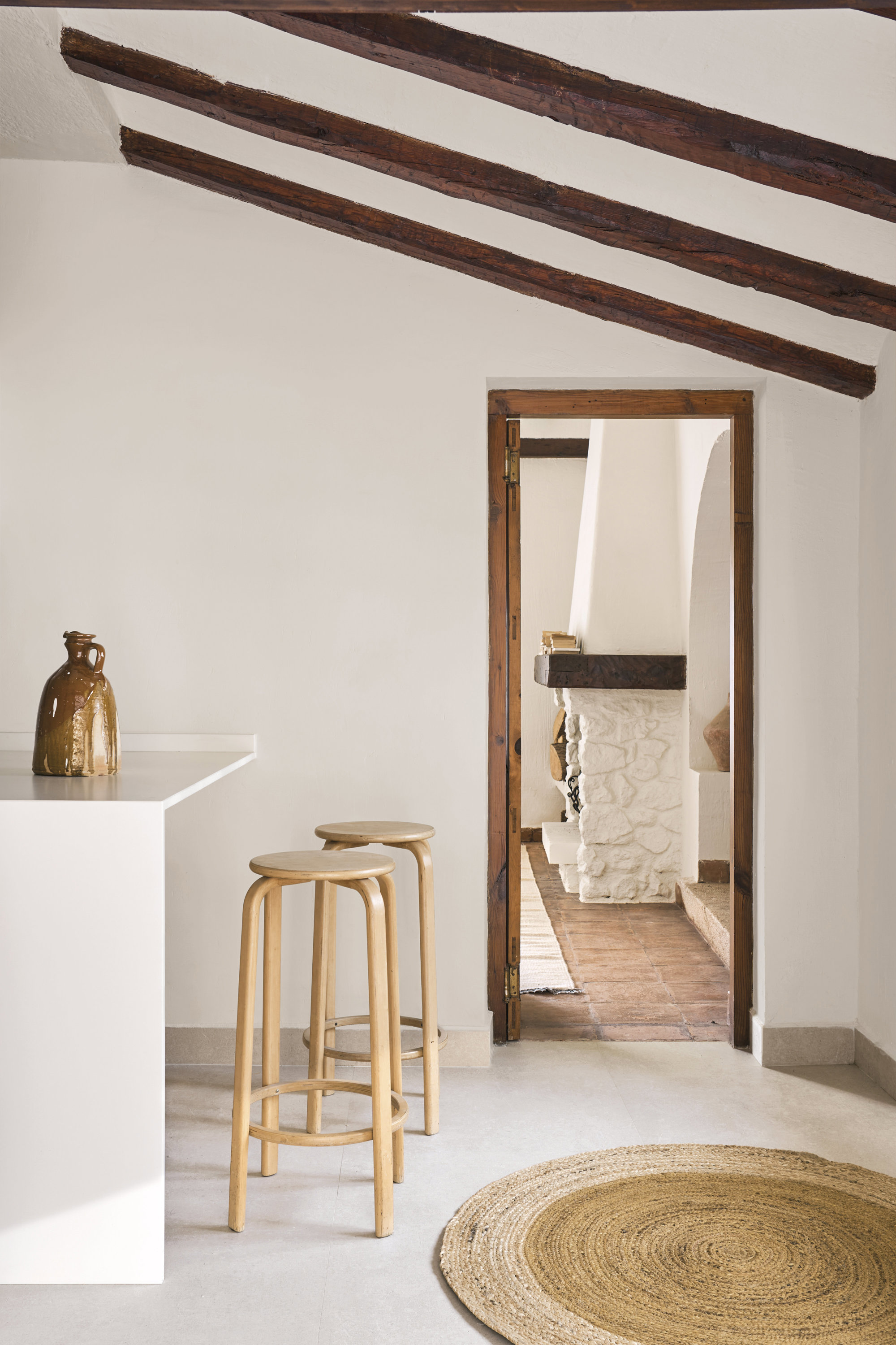  En la cocina, junto a la encimera con Just White de Neolith, pareja de taburetes estilo Alvar Aalto de los años setenta, de IKB 191.