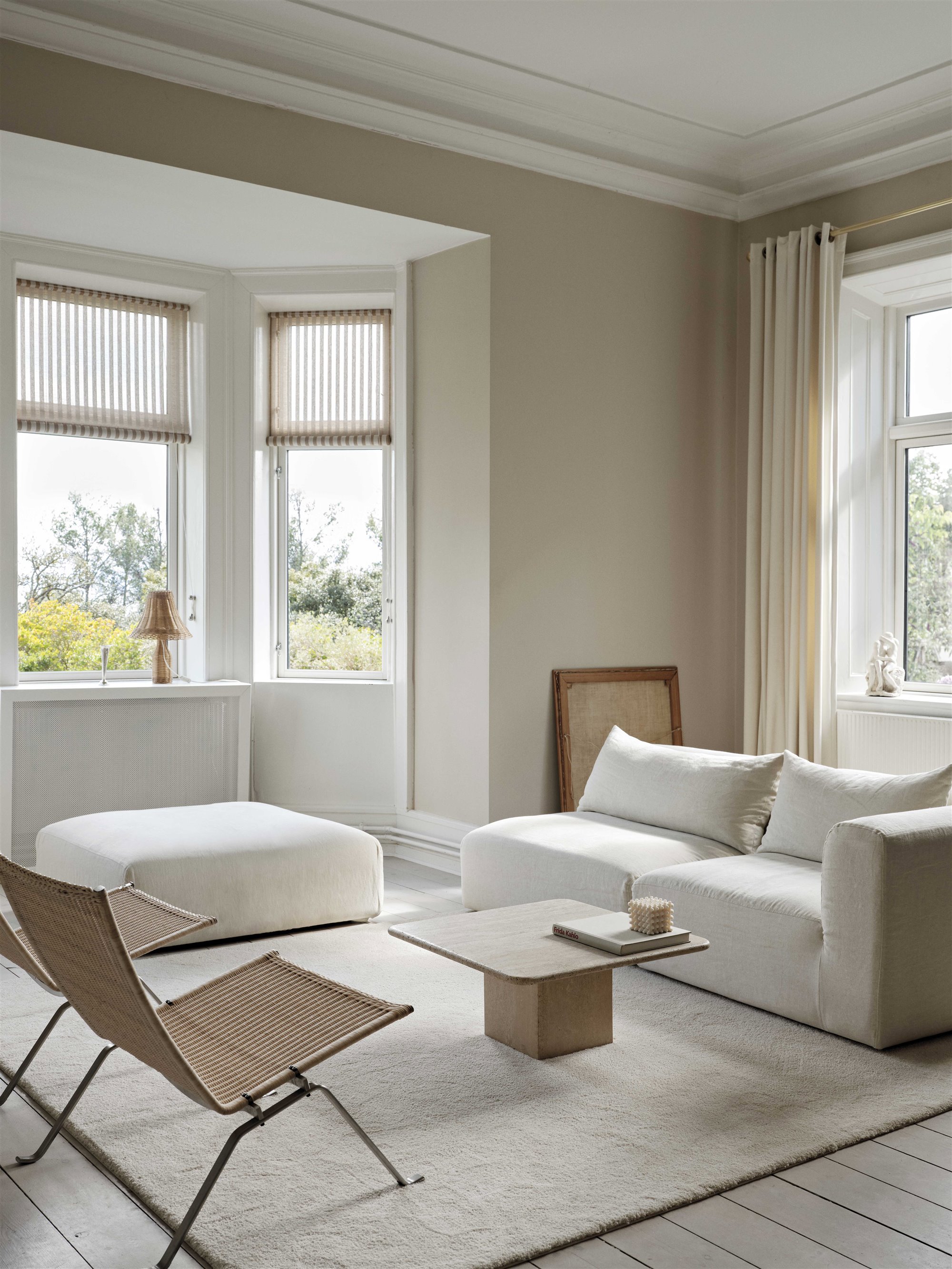 En un extremo de la casa, que se abre al jardín, se encuentra el estar, con un sofá tapizado en blanco, de Tine K Home, y dos sillas PK22, diseño de Poul Kjærholm para Fritz Hansen, que provienen de la casa de la infancia de la propietaria.