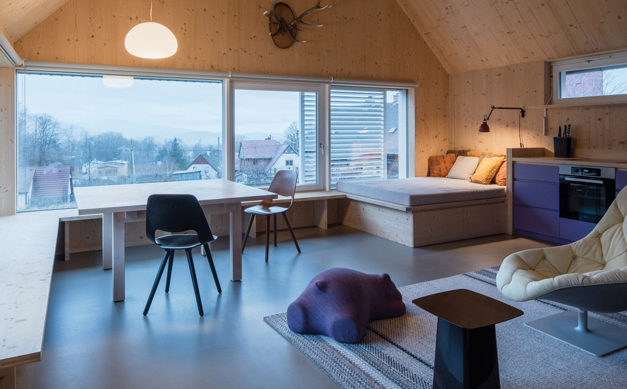 Interiores de madera crean un refugio acogedor que se abre al paisaje a través de grandes ventanas.