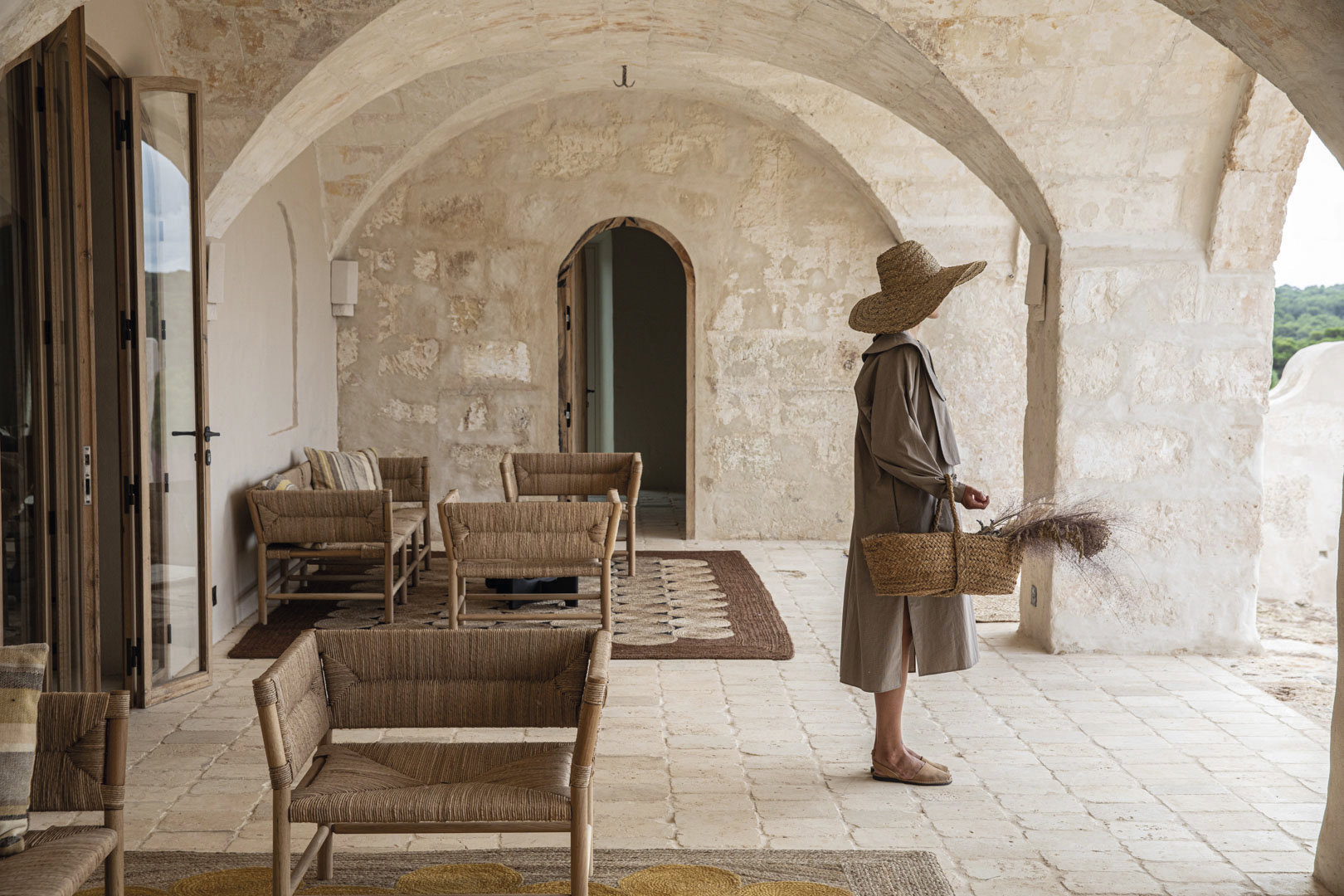 Debajo, el porche bajo las arcadas de piedra que se han conservado intactas. Muebles de madera, de Éditions Midi, y alfombras de yute natural, de Élitis