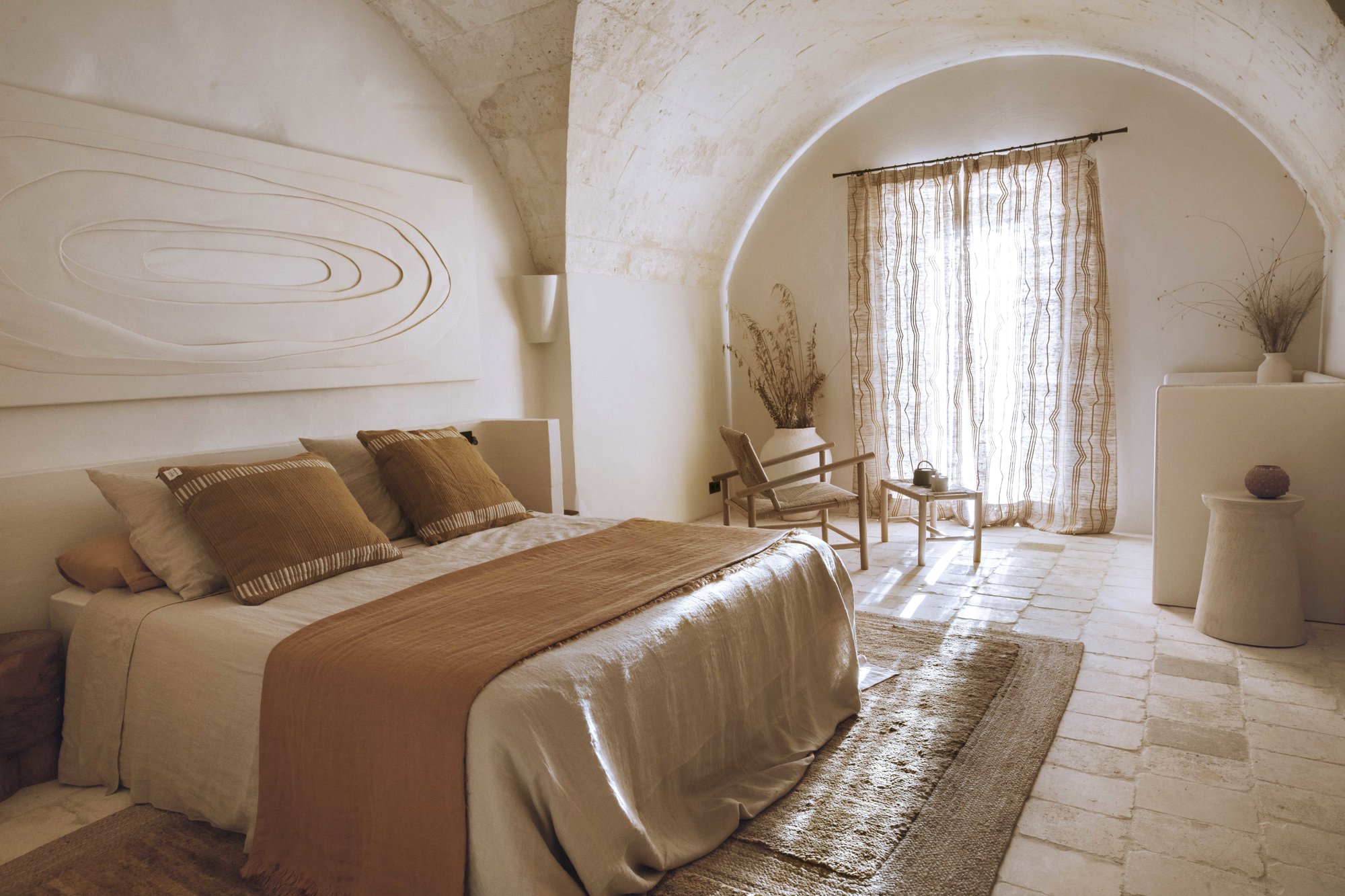 En la suite Artesana, obra textil de Adriana Meunie con sábanas y cortinas de lino, de Magic Linen. Minibar a medida, de Gavila Carpintería, y butaca de madera, de Éditions Midi