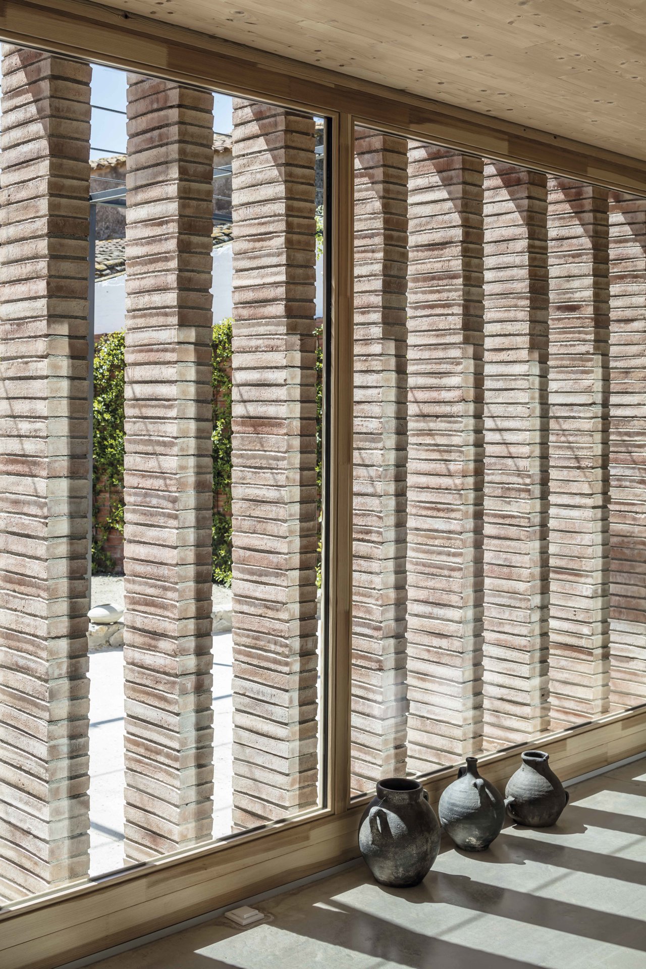 Las pilastras de ladrillo cerámico de la Casa AA en Ullà (Girona) configuran una fachada interior singular
