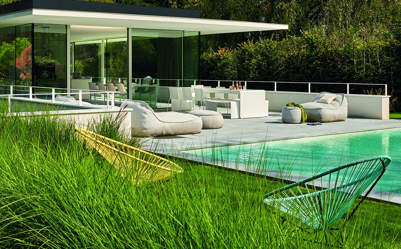 Casa de Bruno Erpicum con dos butacas Acapulco en primer plano y los sofás Float, de Francesco Rota para Paola Lenti, junto a la piscina.