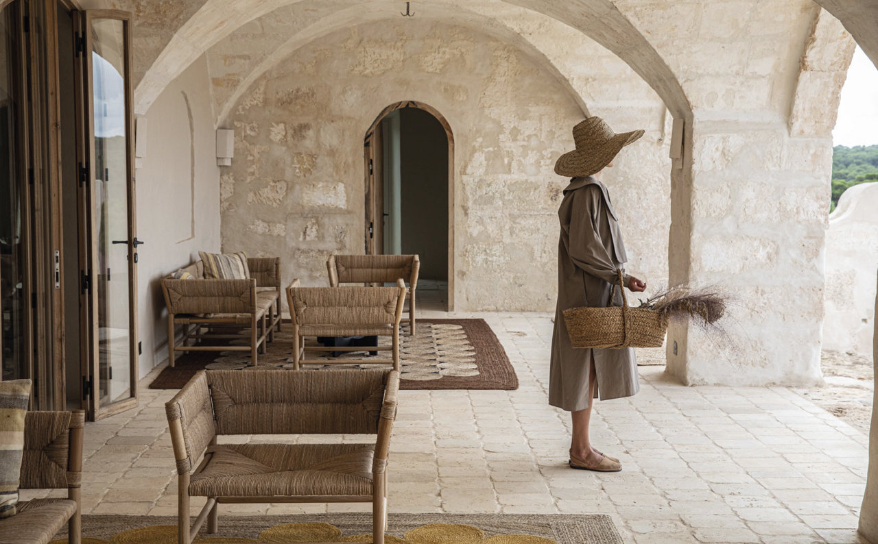 Debajo, el porche bajo las arcadas de piedra que se han conservado intactas. Muebles de madera, de Éditions Midi, y alfombras de yute natural, de Élitis