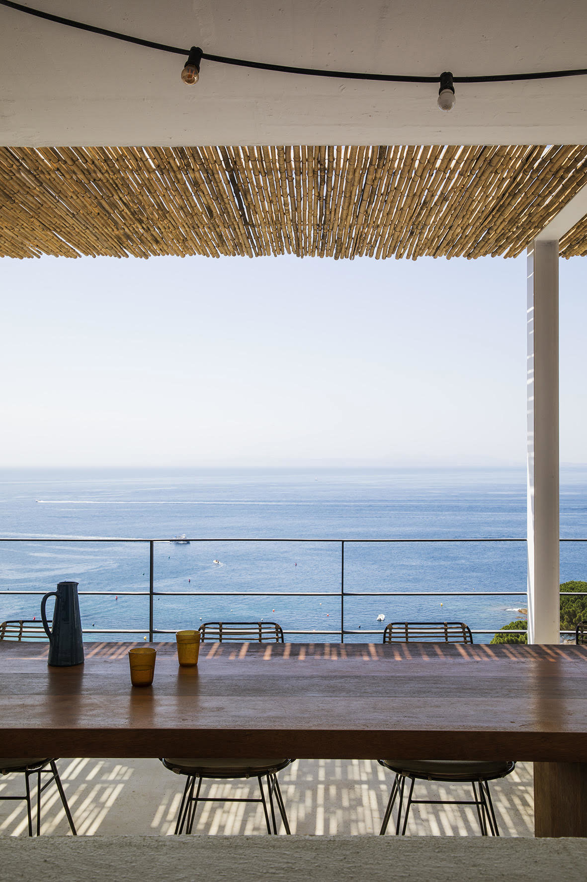terraza con vistas al mar y una mesa de madera alargada.
