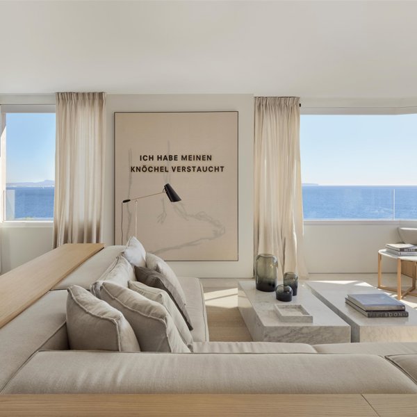 salón minimalista con vistas al mar sofá banco de madera y color blanco roto