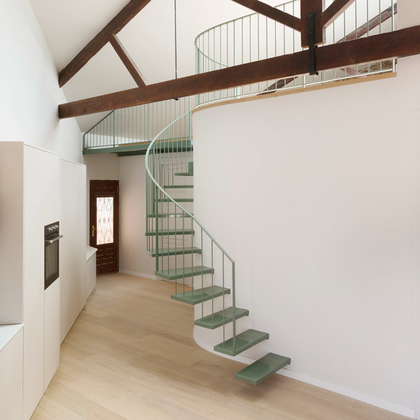 Todo gira alrededor de la escalera verde que sube al altillo en esta casa de estilo industrial